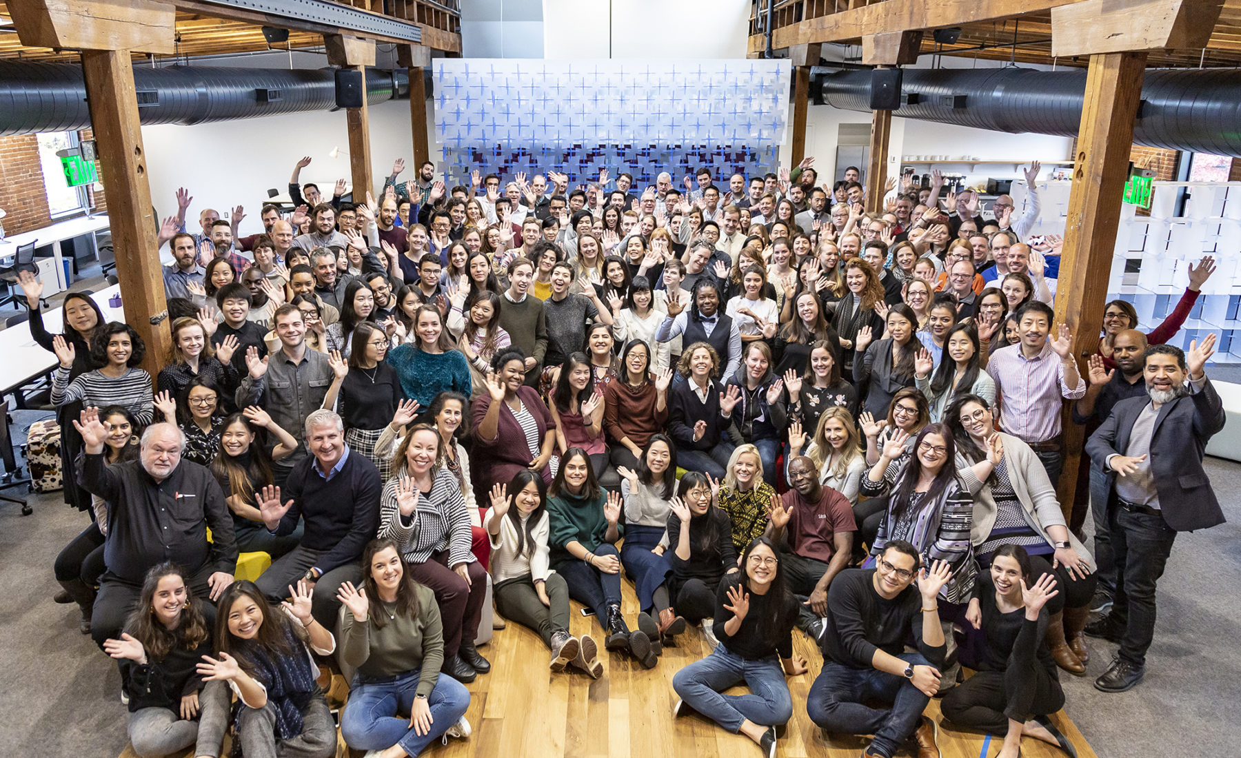 Photo taken from above of Sasakians gathered in the Incubator waving at the camera