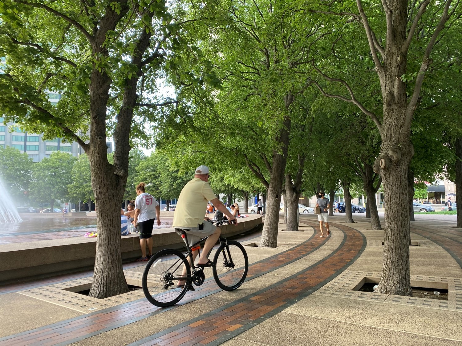 photography of cyclist riding bicycle around circular fountain