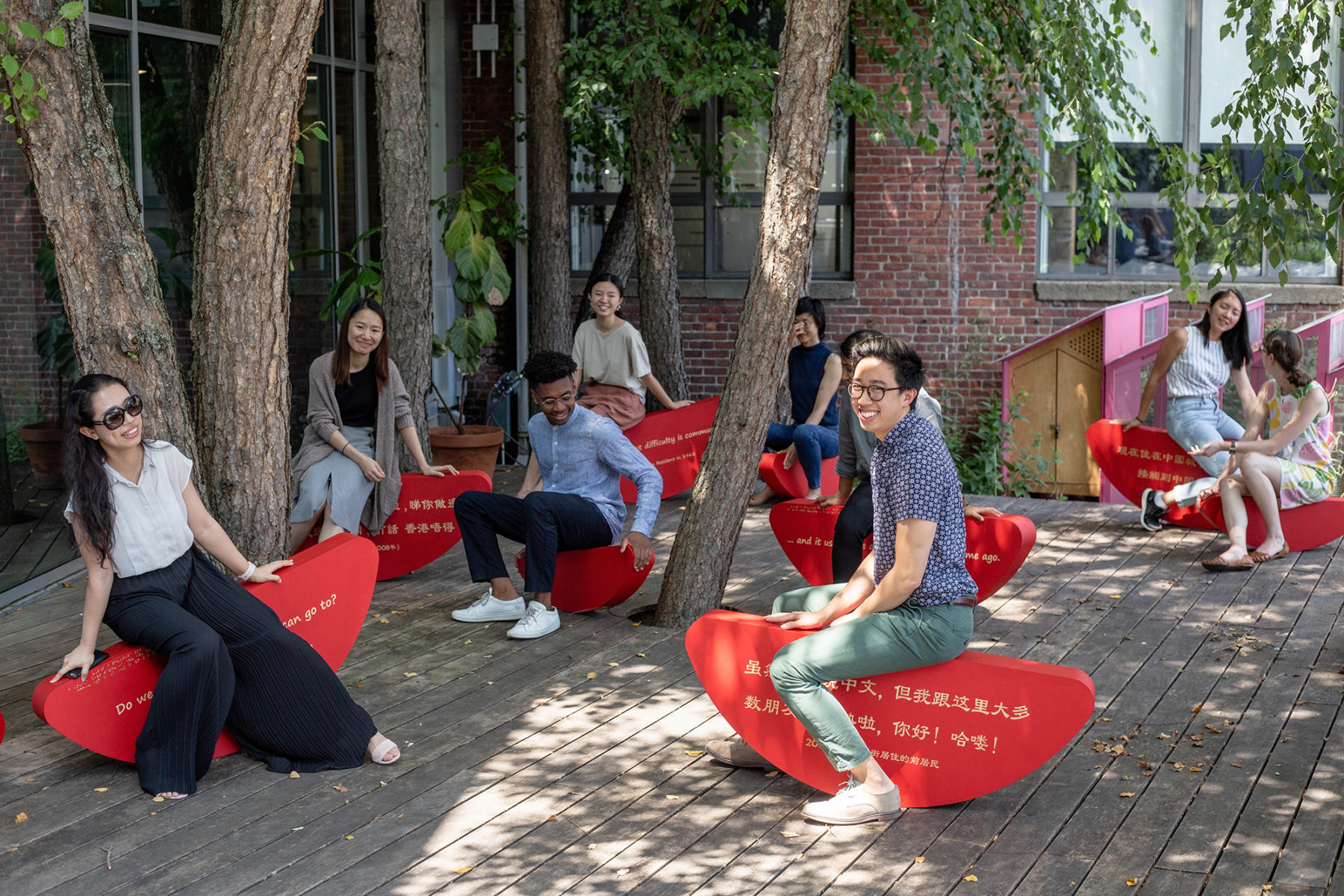Photo of a group of Sasakians and interns sitting on custom-made red benches on a deck