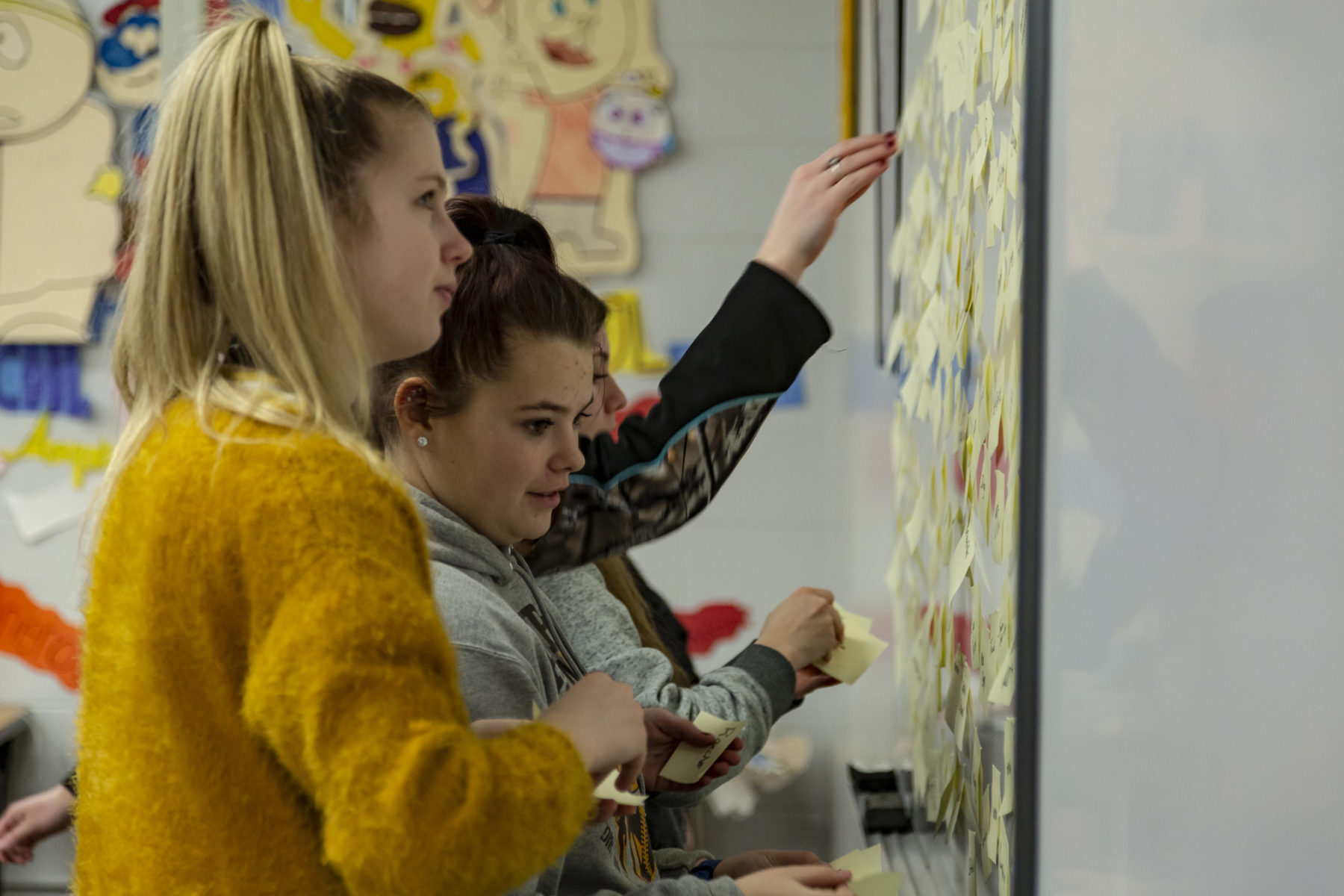 Students stick sticky notes to a whiteboard