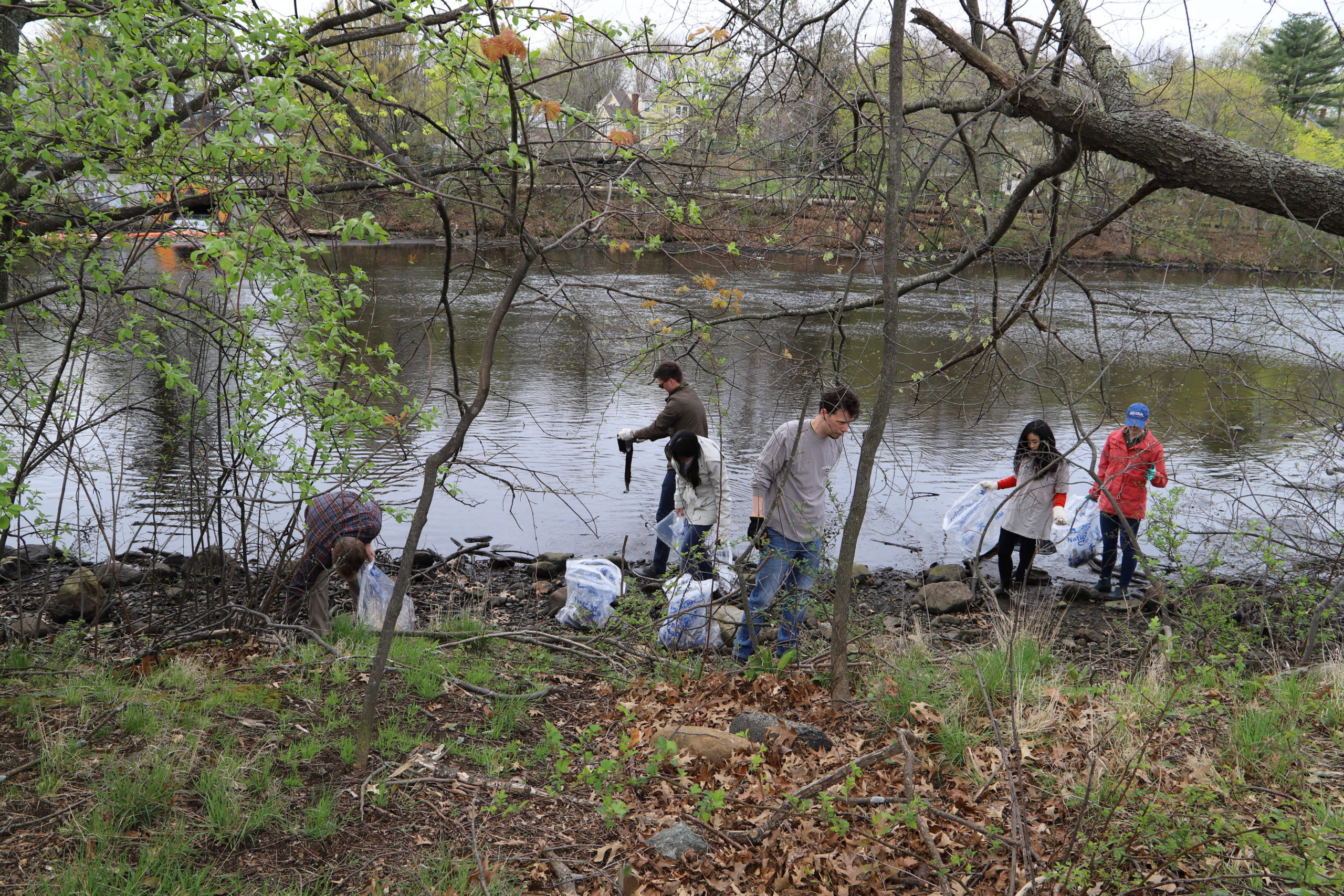 Group of people picking up trash along riverside