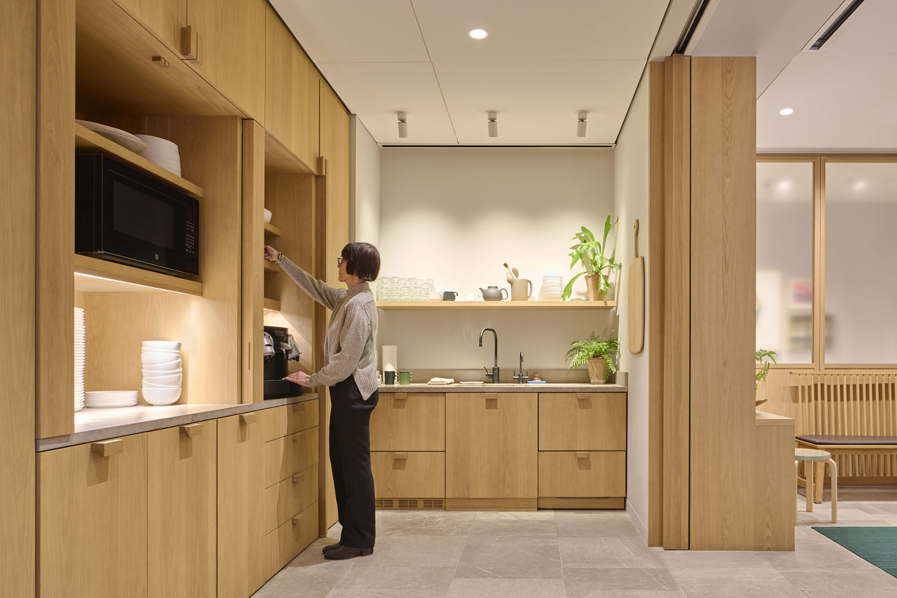 woman reaching for cabinet, kitchen sink in background