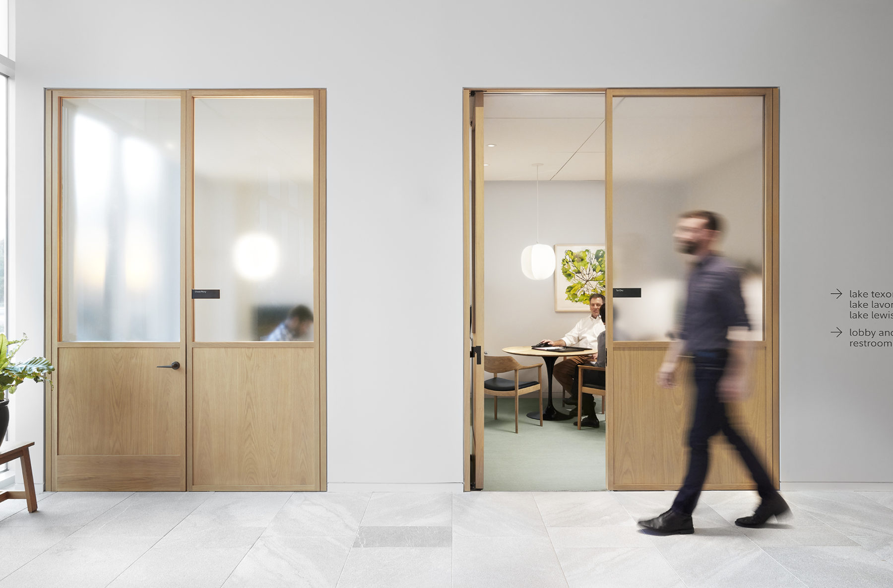 man walking in front of private offices, frosted glass