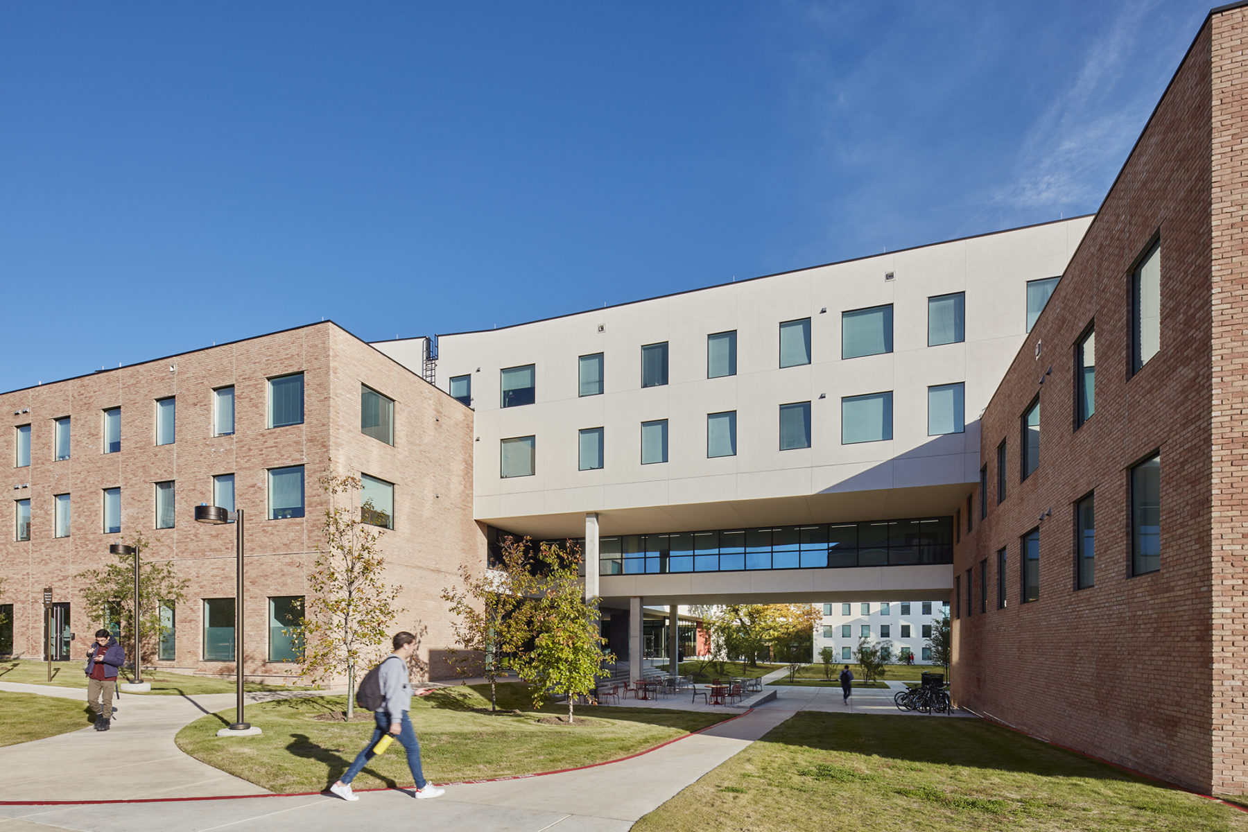 student walking down path towards overhang and courtyard