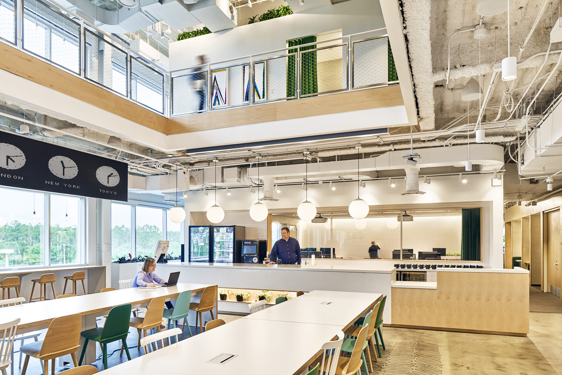 double-height atrium showing common area tables and meeting space beyond