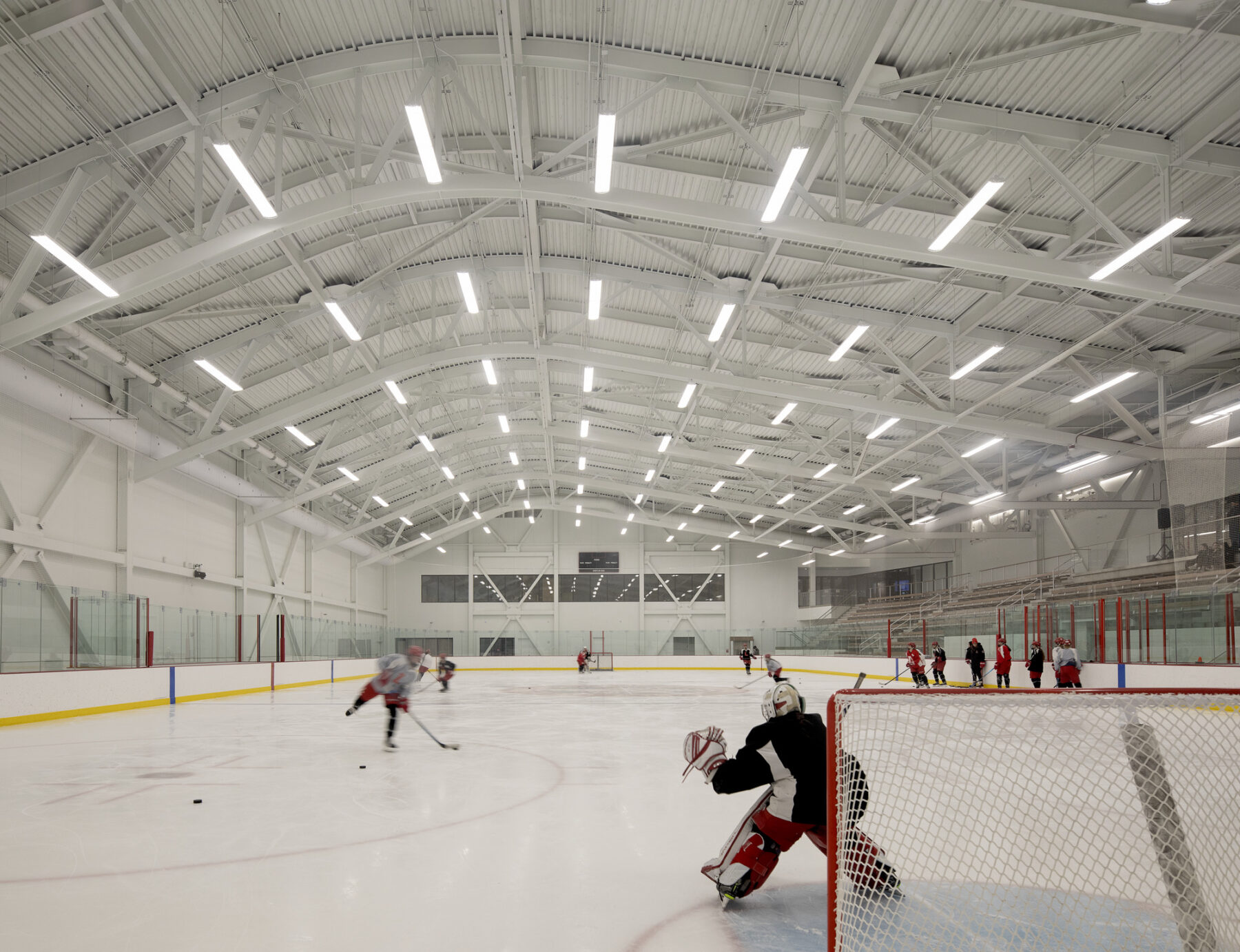 Interior photograph of ice hockey arena with curved ceiling above the rink