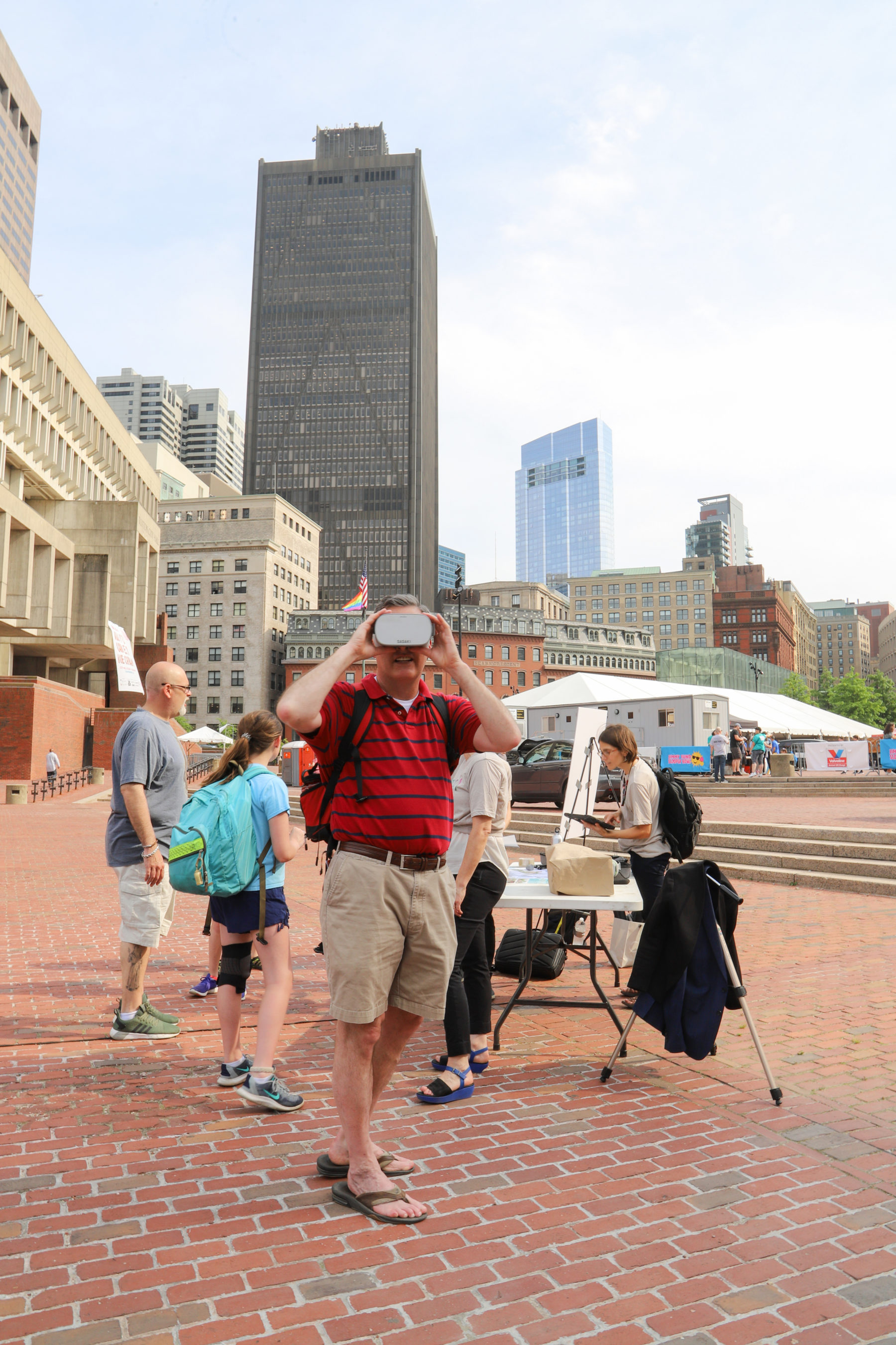 Man looking through VR goggles with tall buildings in the background