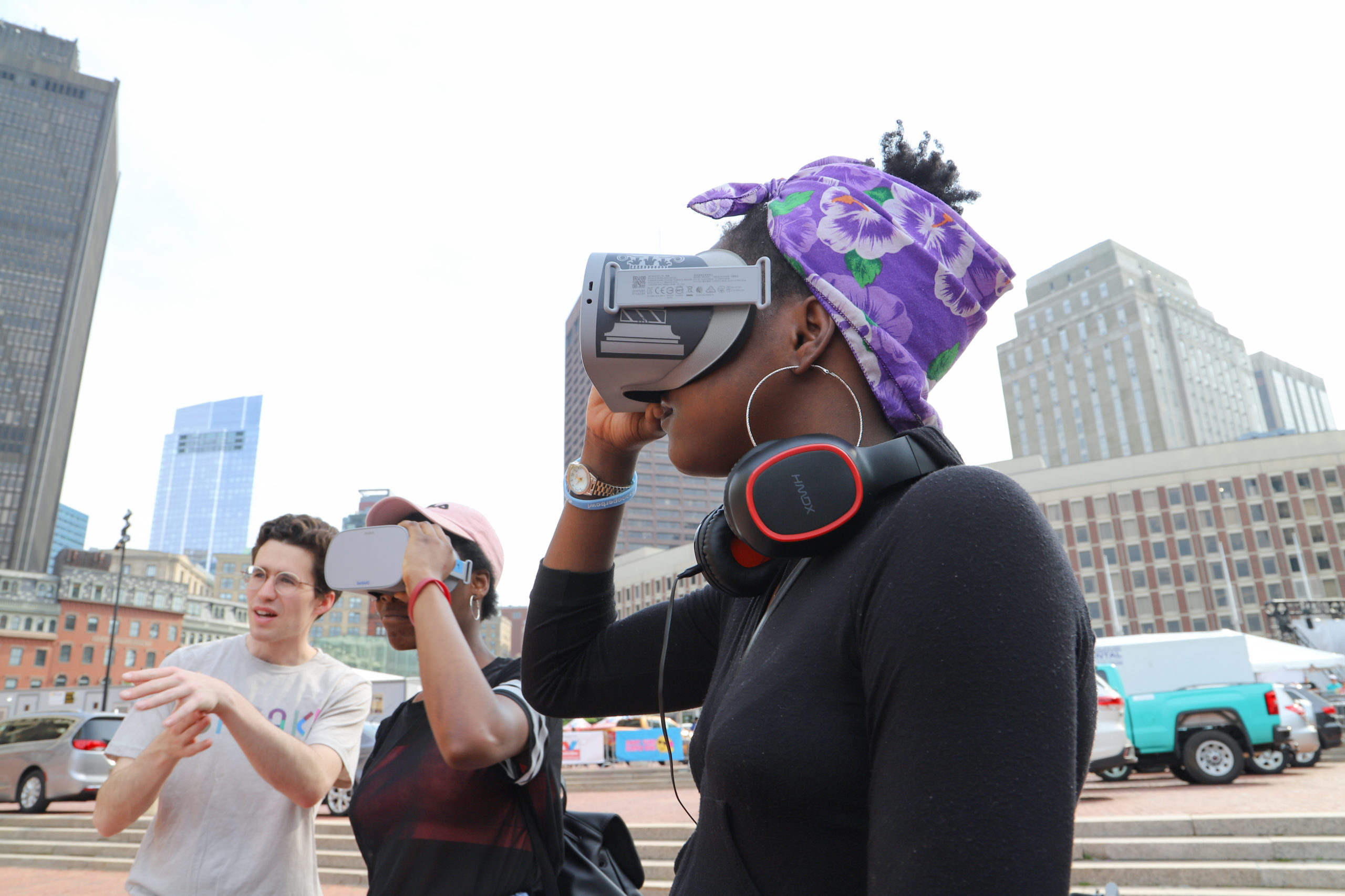 Woman looking through VR goggles with two people behind her also looking through VR goggles