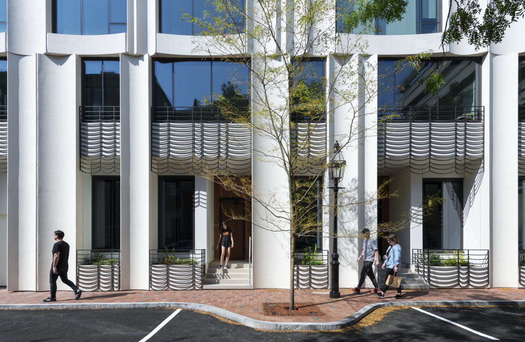 exterior elevational photo of town house entrances. two people walk together on the right side of the image.