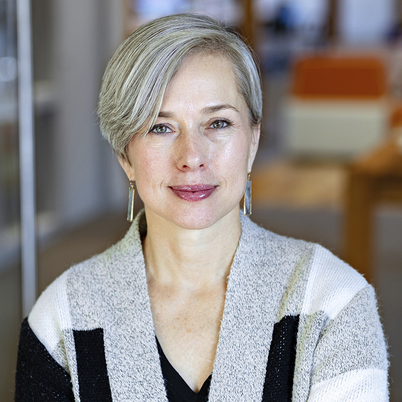 Headshot of woman with her arms folded wearing a gray sweater