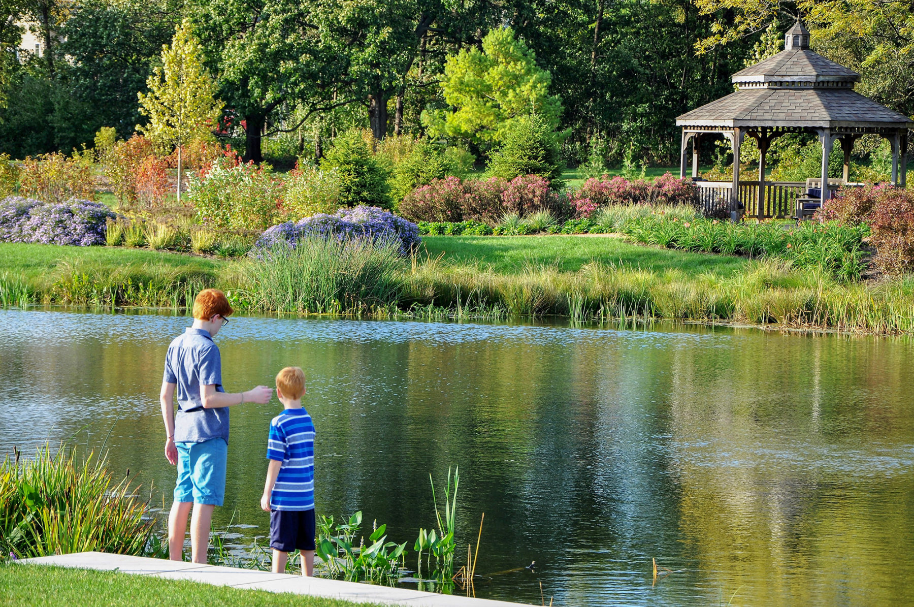 two boys standing next to a pond
