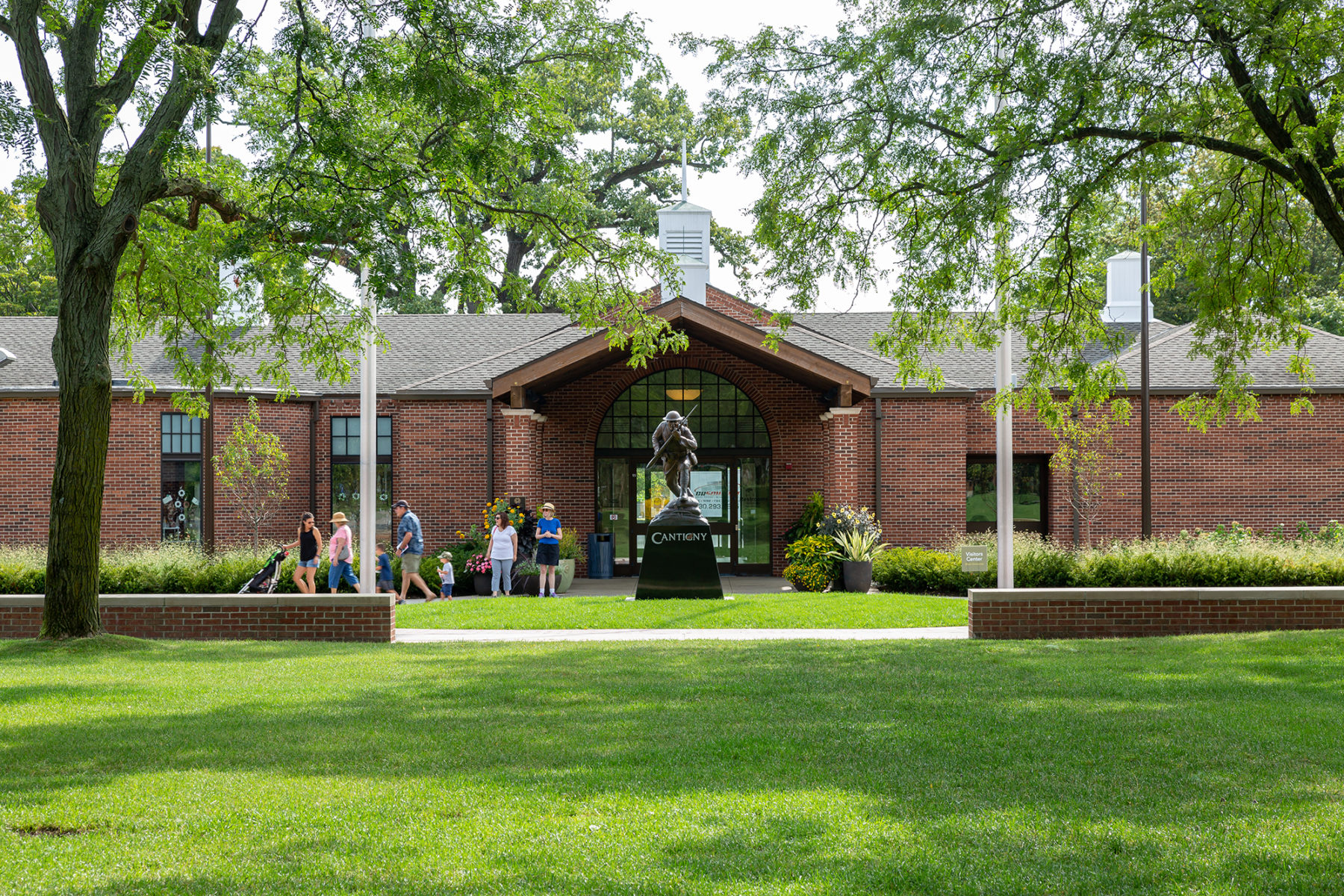 people exit a building with a statue in front