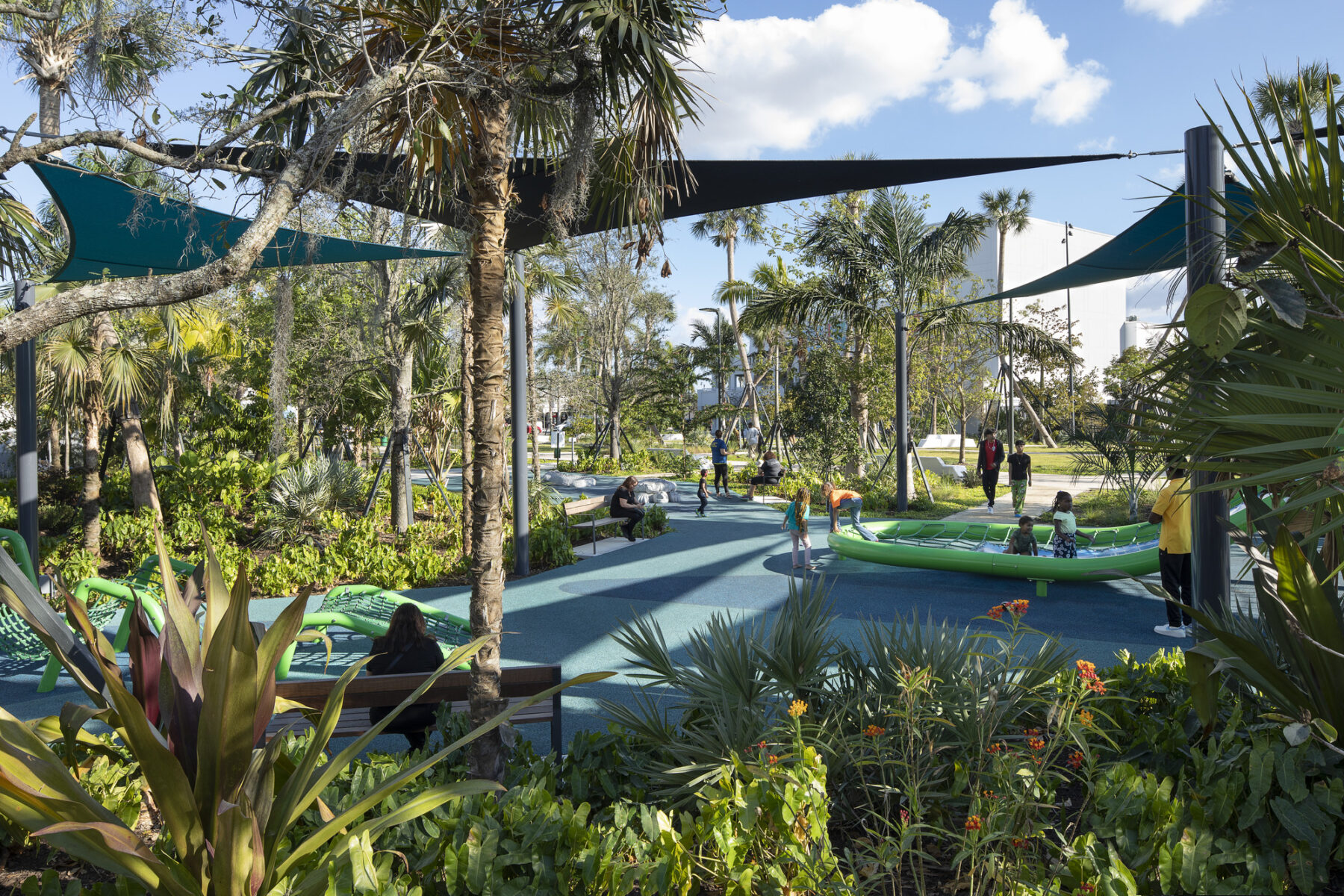 perspective photograph of playground with woman sitting on bench in foreground