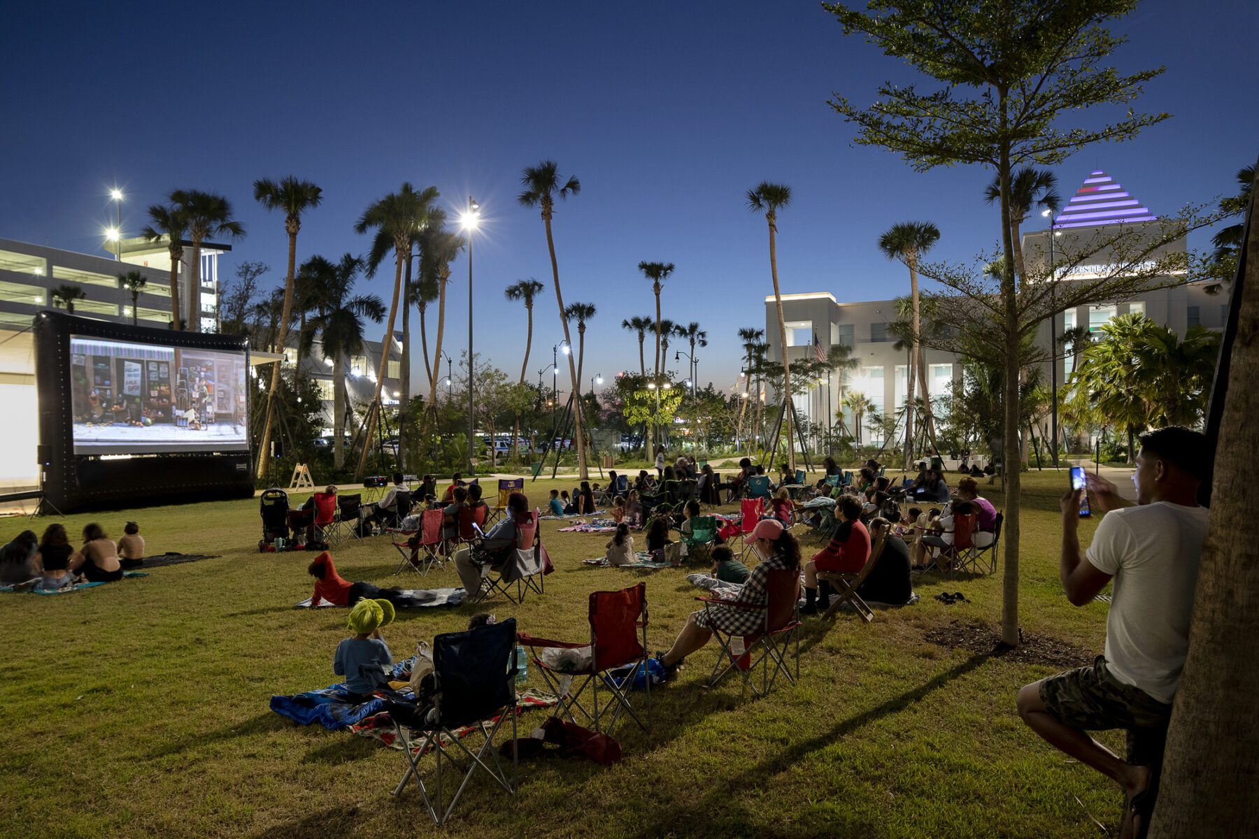 photograph of park visitors gathering on lawn space during an evening outdoor movie screening
