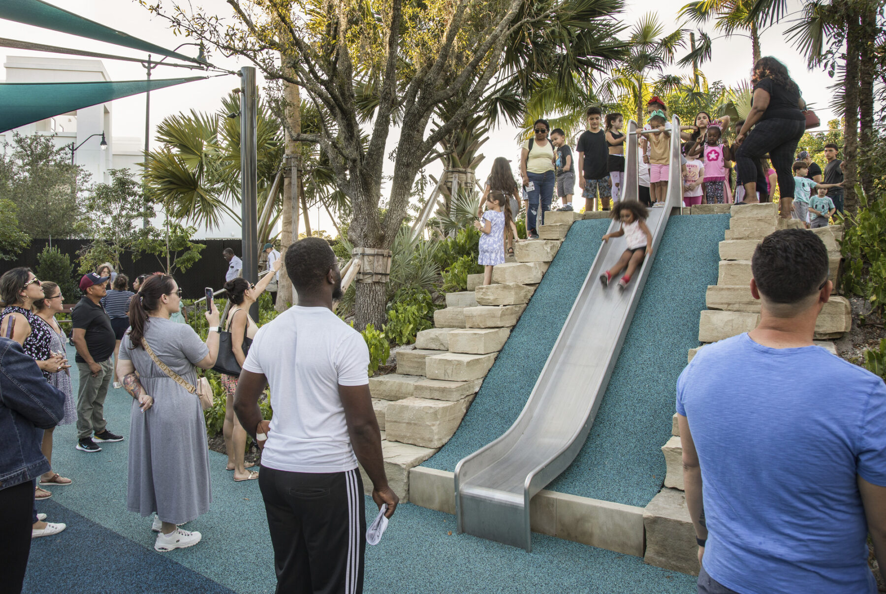 children going down slide integrated on a park mound