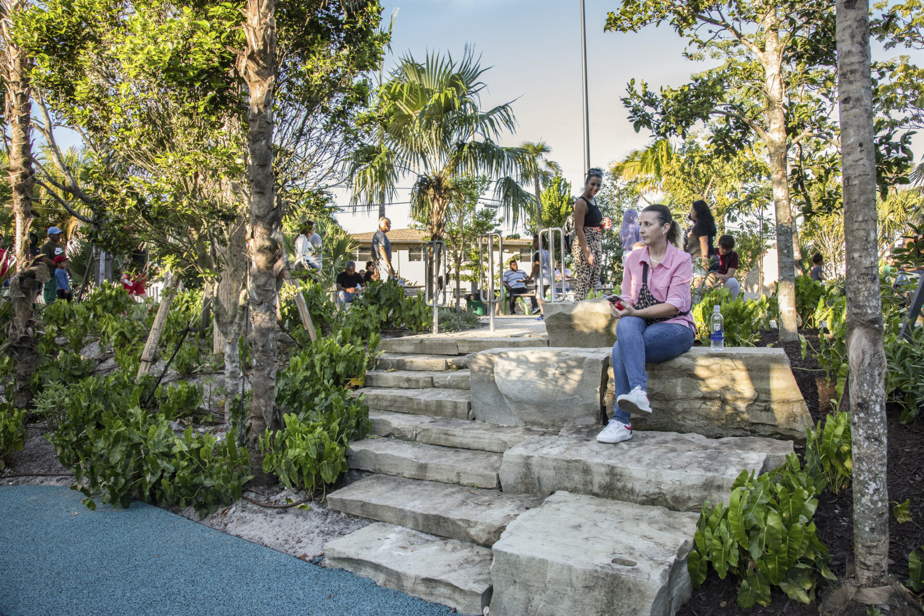 photograph of adult sitting on rock features of playground