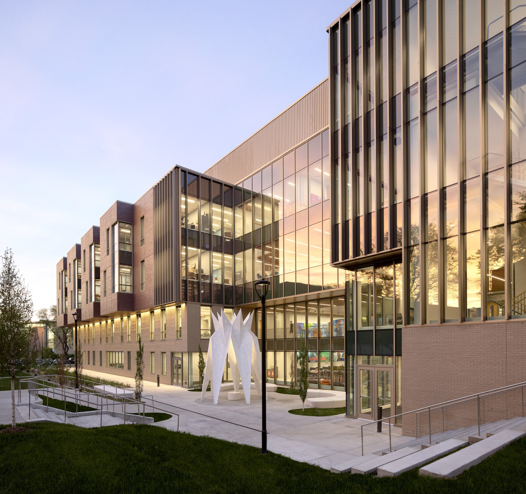 Photograph of building exterior facade at sunset with colorful light reflecting off the glass