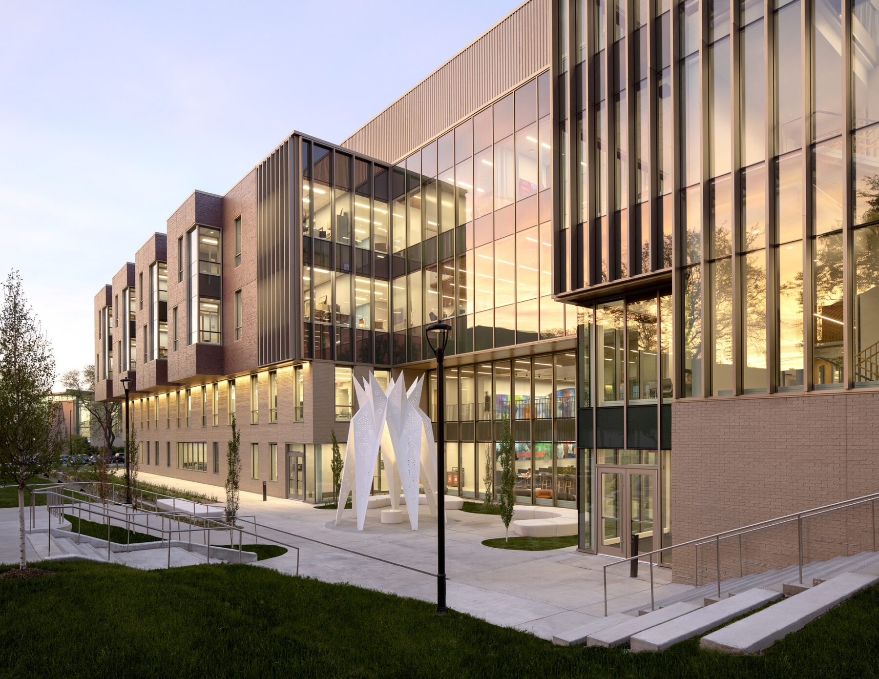 Photograph of building exterior facade at sunset with colorful light reflecting off the glass