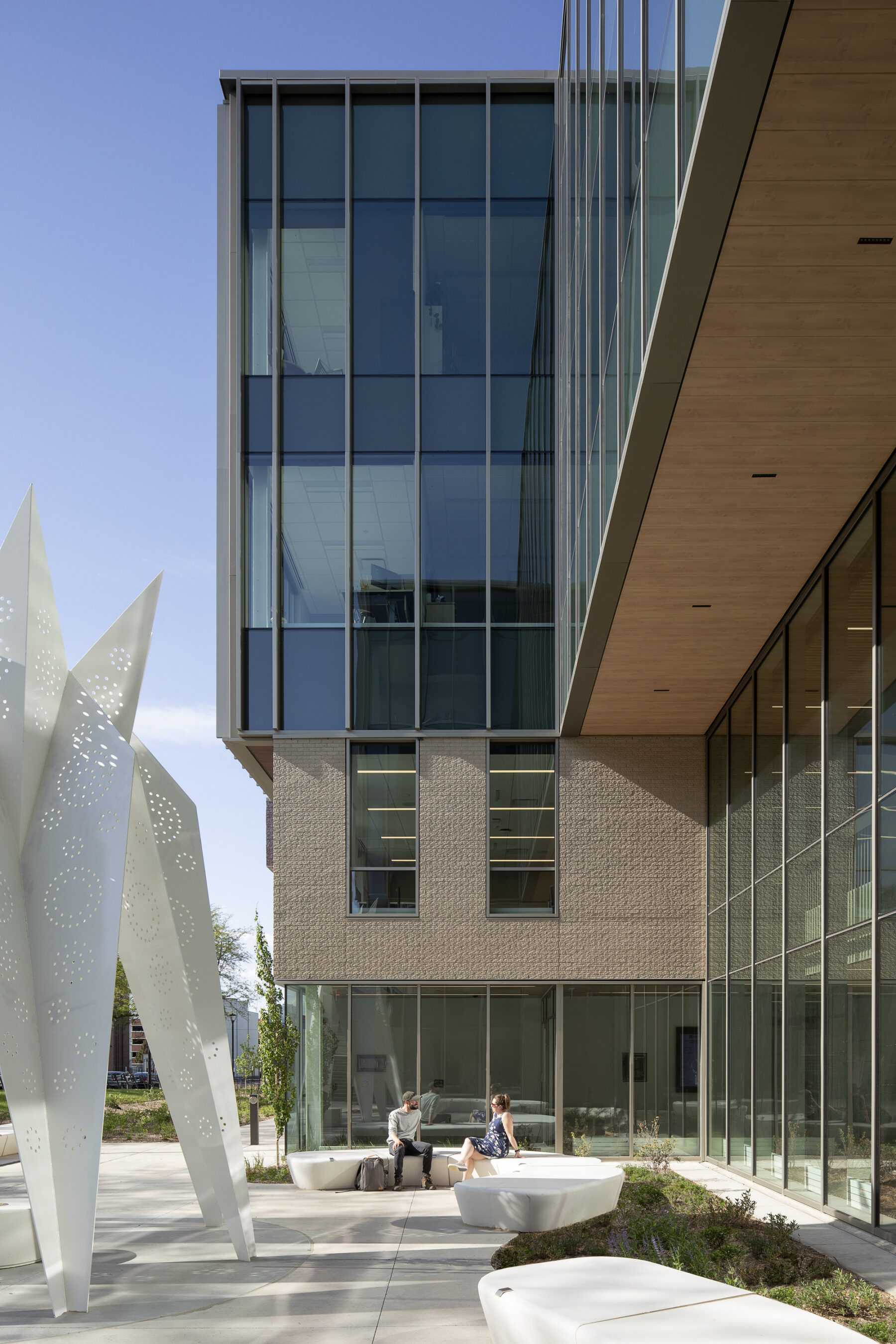 Photo viewing the terrace at the building's main entrance with seating areas and large decorative sculpture