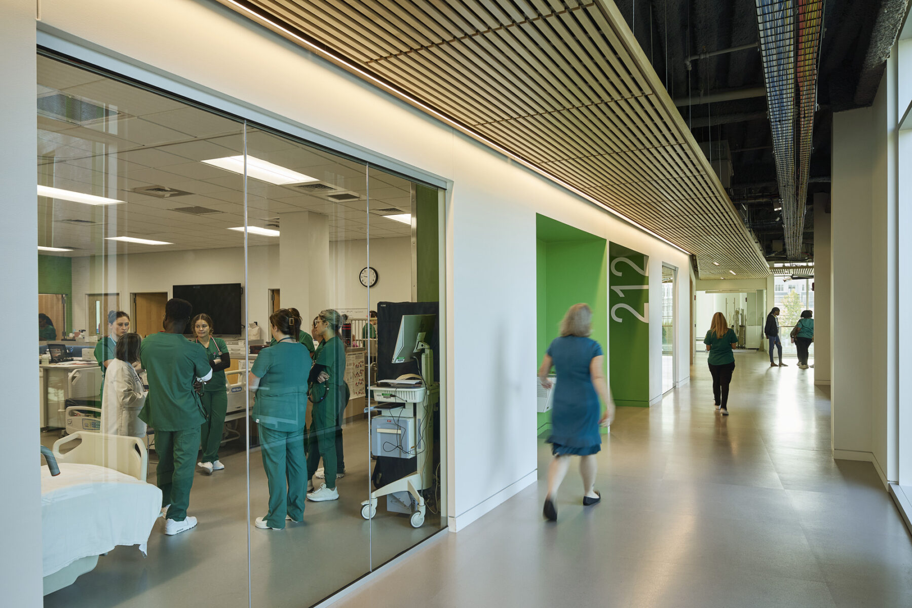 View of corridor outside of nursing suite with floor to ceiling windows allowing views in to the class activity