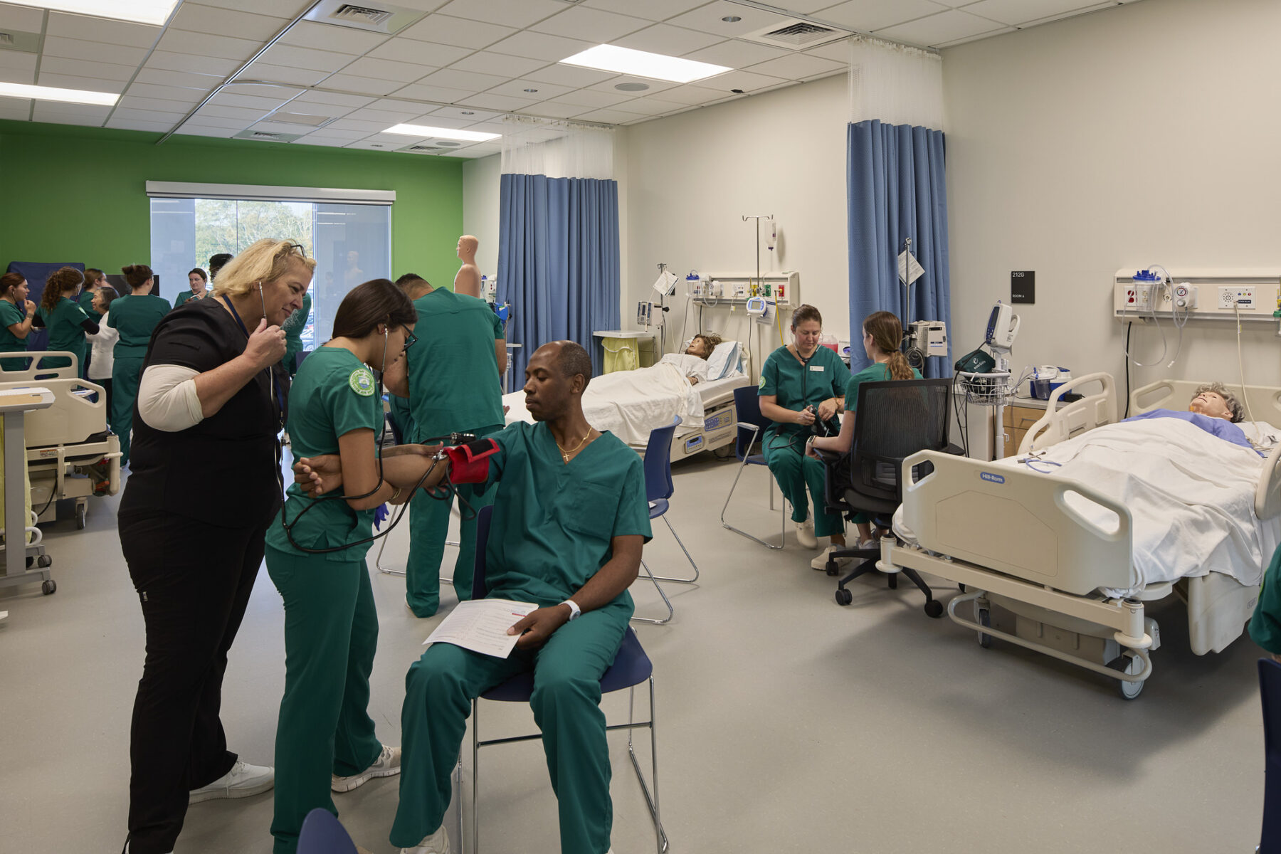 Nursing students in groups take turns measuring blood pressure