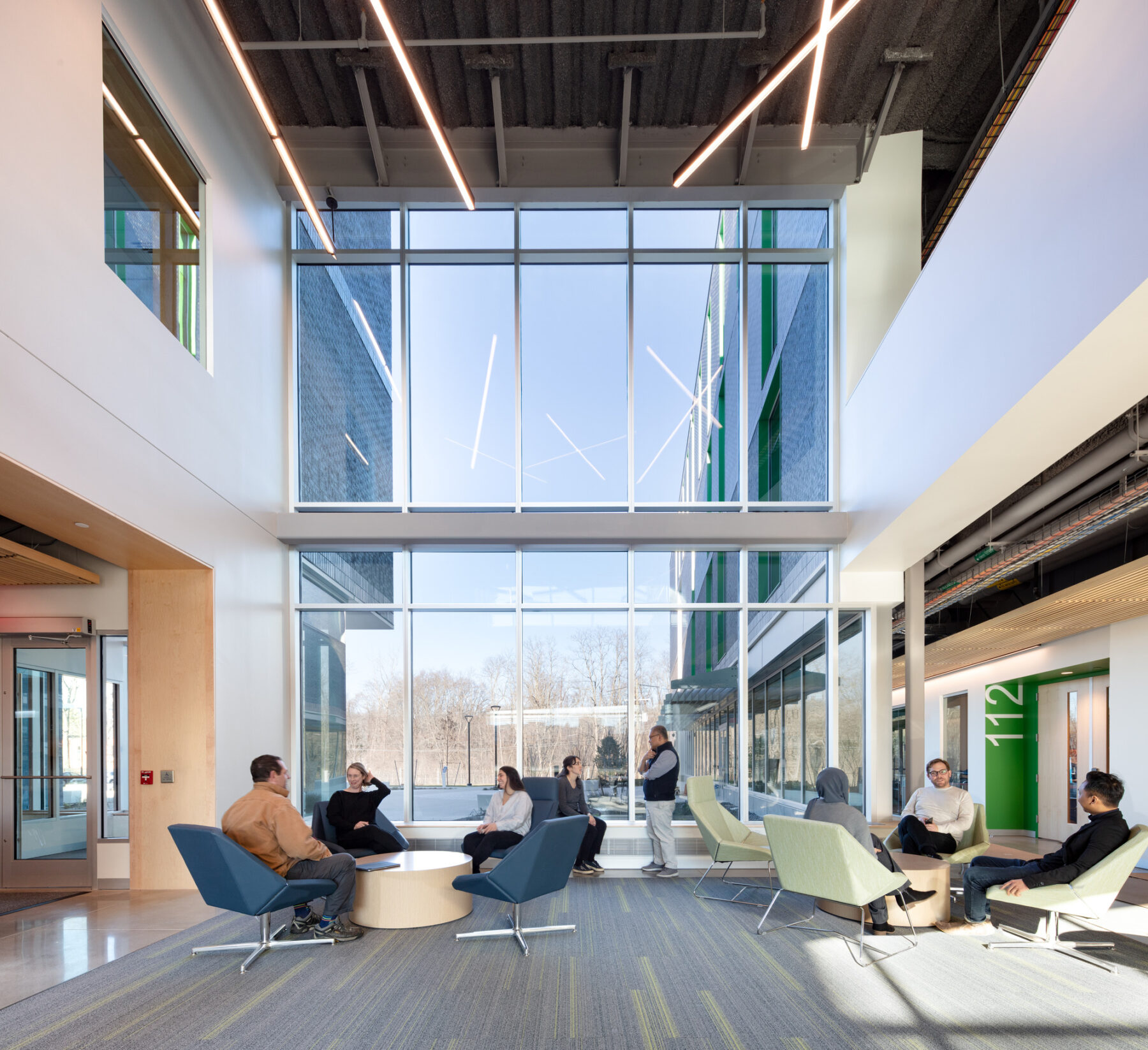 photograph of student socializing in central lobby featuring high ceilings and large windows, and custom furnishings