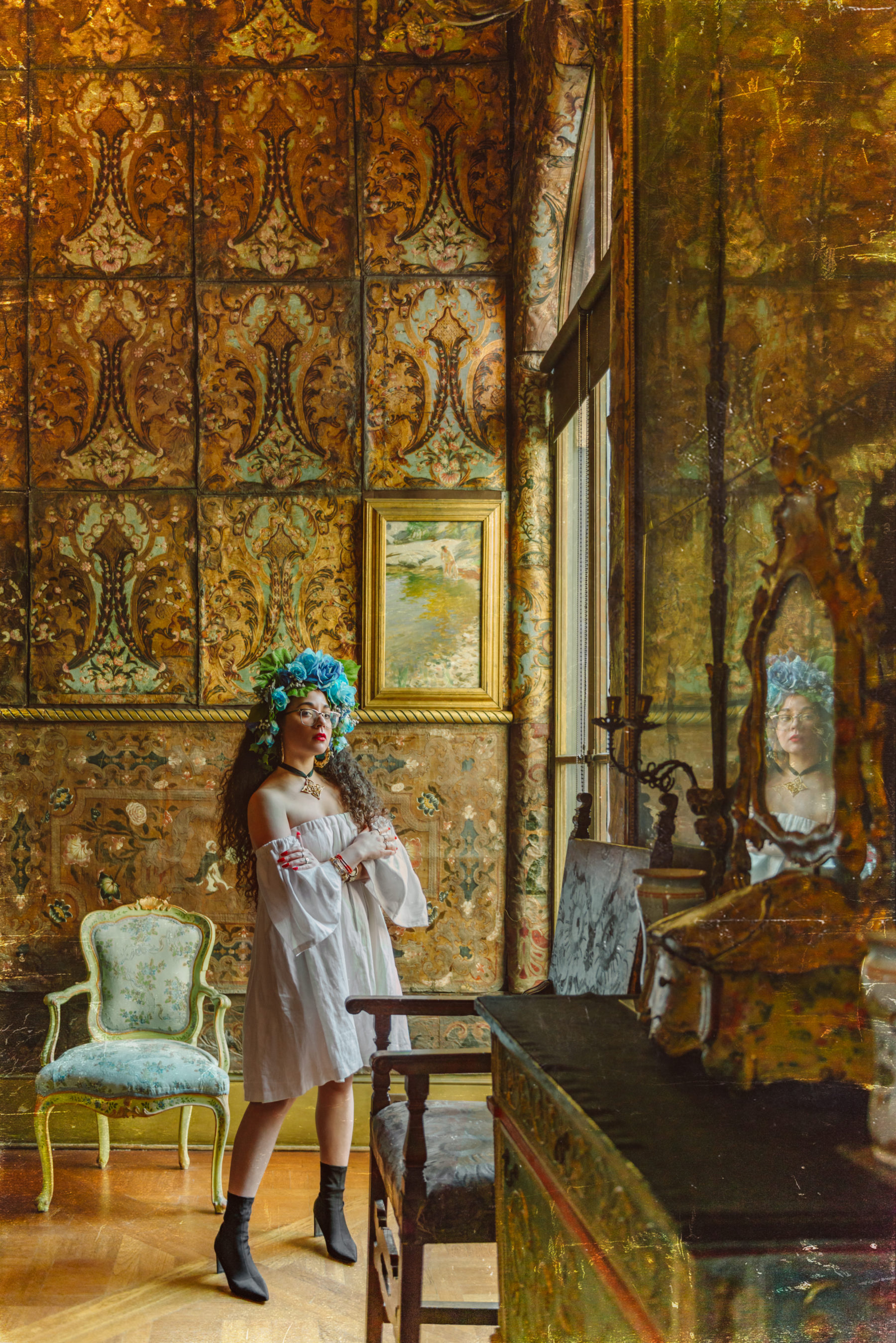 Photo of Paloma in golden room with her image reflected in a mirror