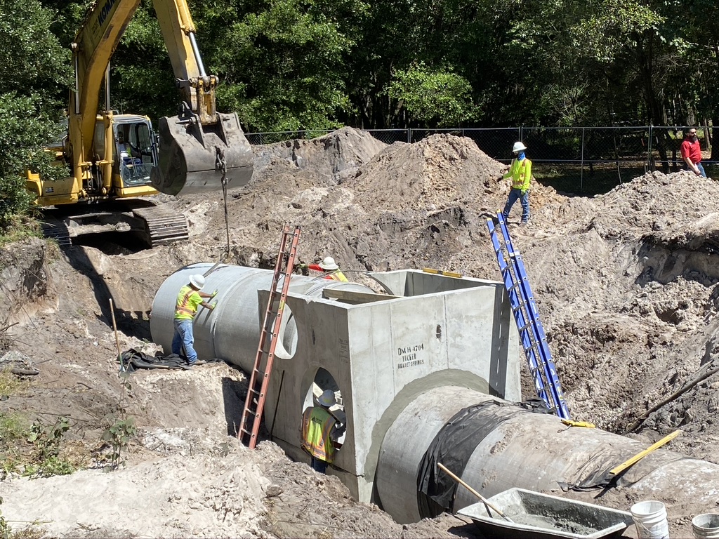 a construction crew installing large pipes into the ground