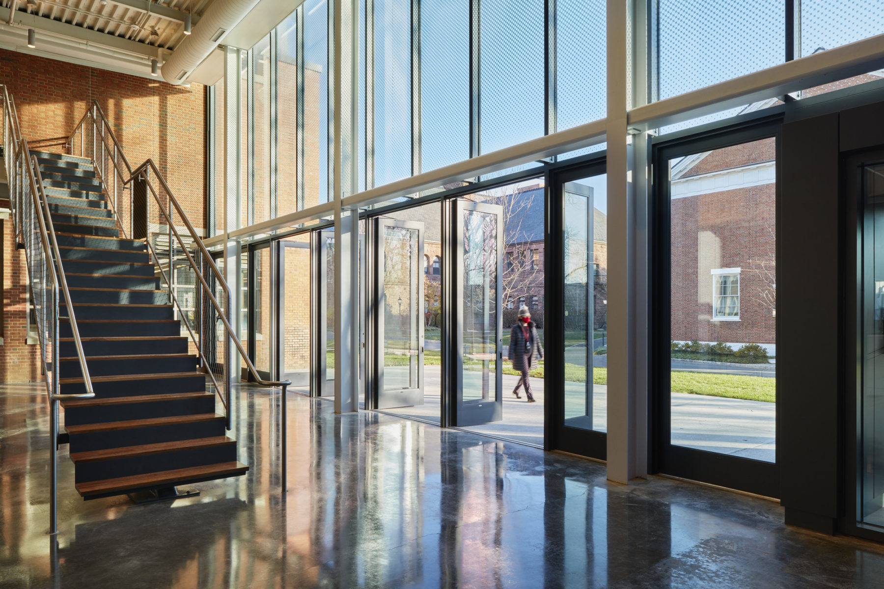 Interior photo of building entry looking out to street. A person walks by