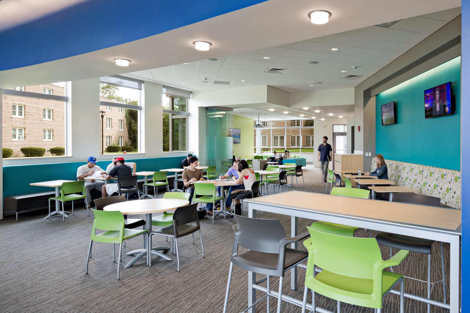 Interior photo of collaborate space. Students sit in groups at multiple tables.