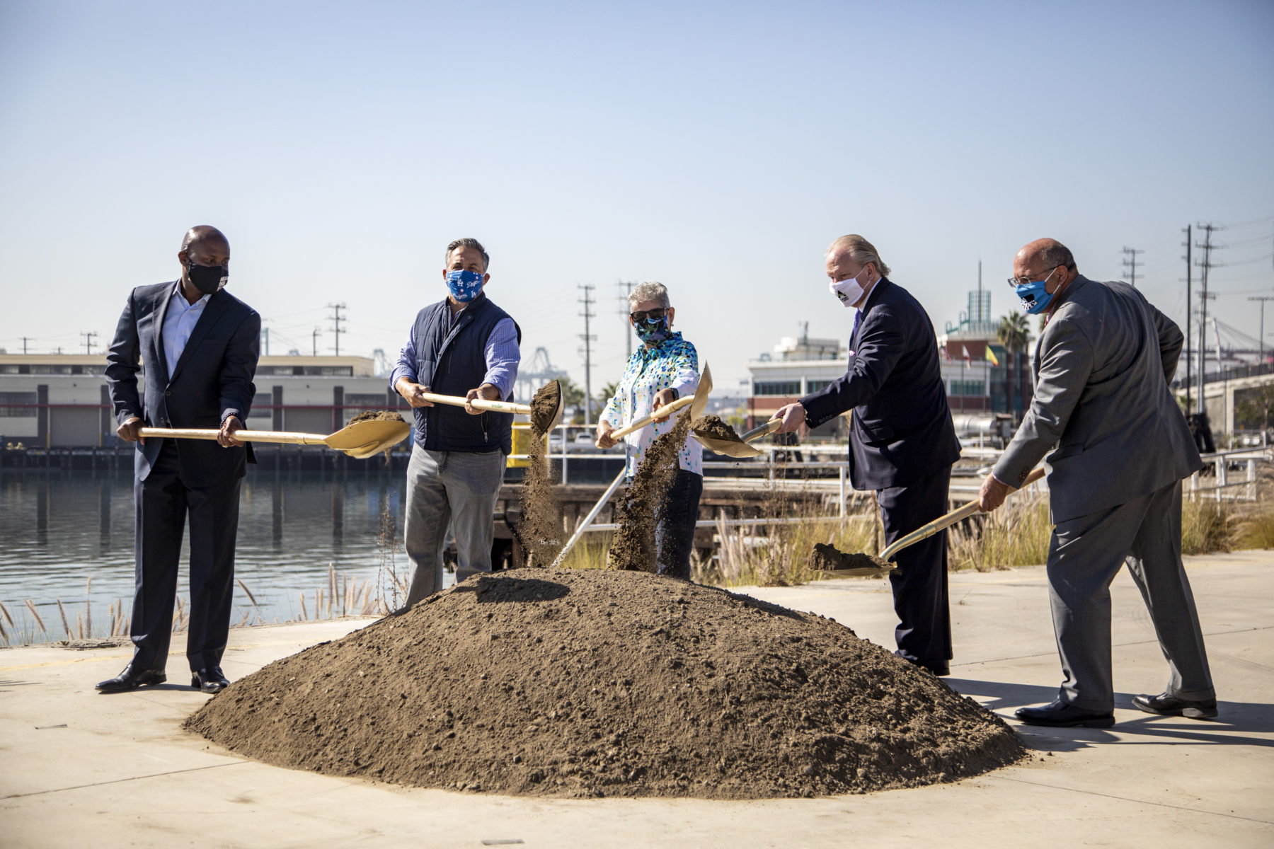 Five people with shovels in front of dirt pile during groundbreaking ceremony