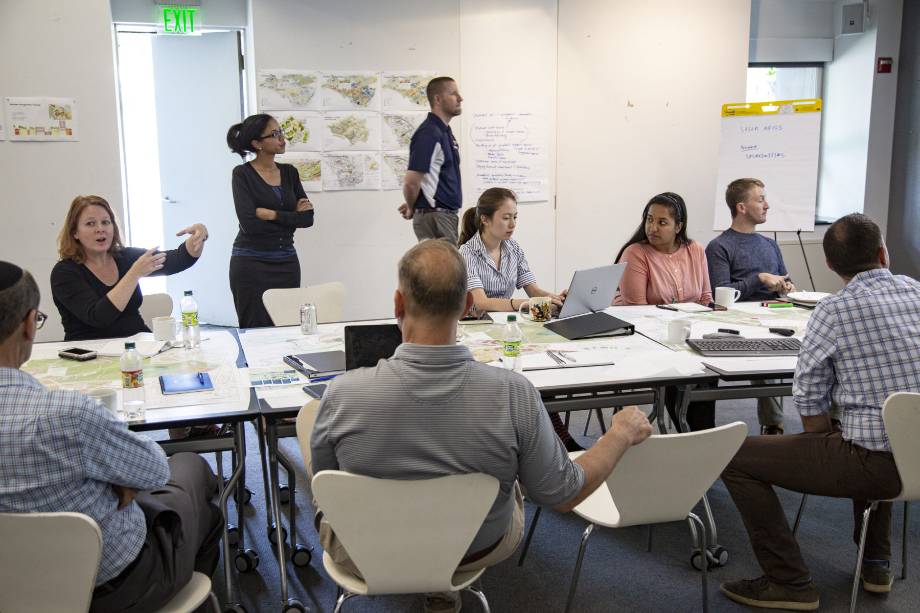 photo of team holding a work session around a table looking at project materials