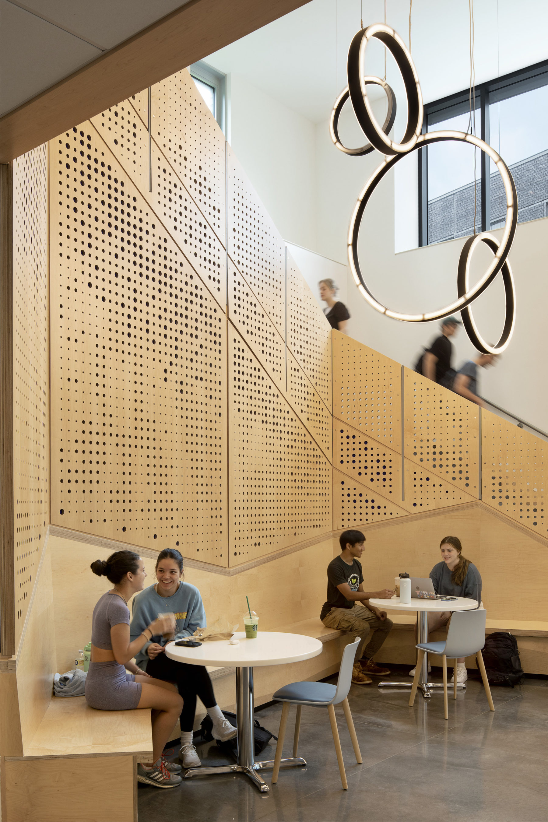 interior photo of students sitting in cafe area in nook framed by staircase