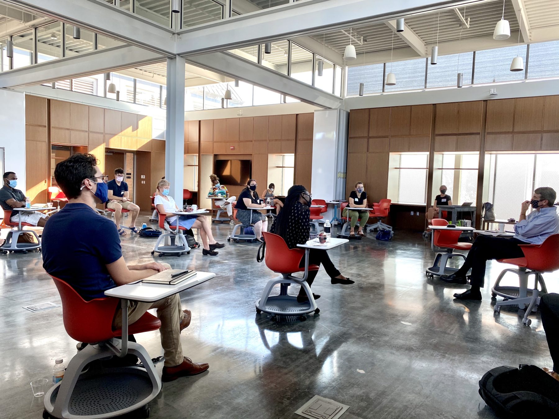 people at desks, sitting far apart from each other with masks on