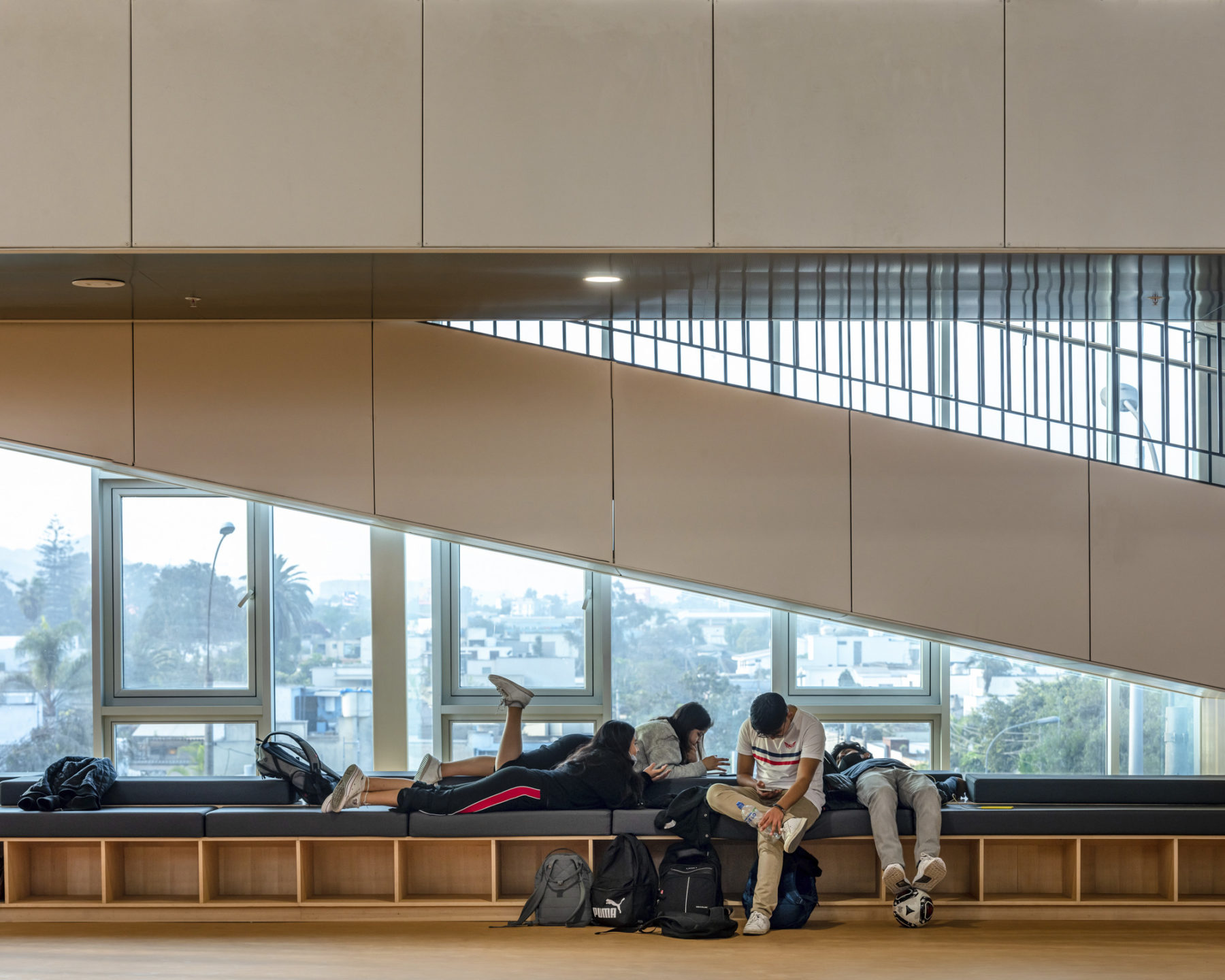 interior photo of seating area next to basketball court. a group of students lounge together on the bench.