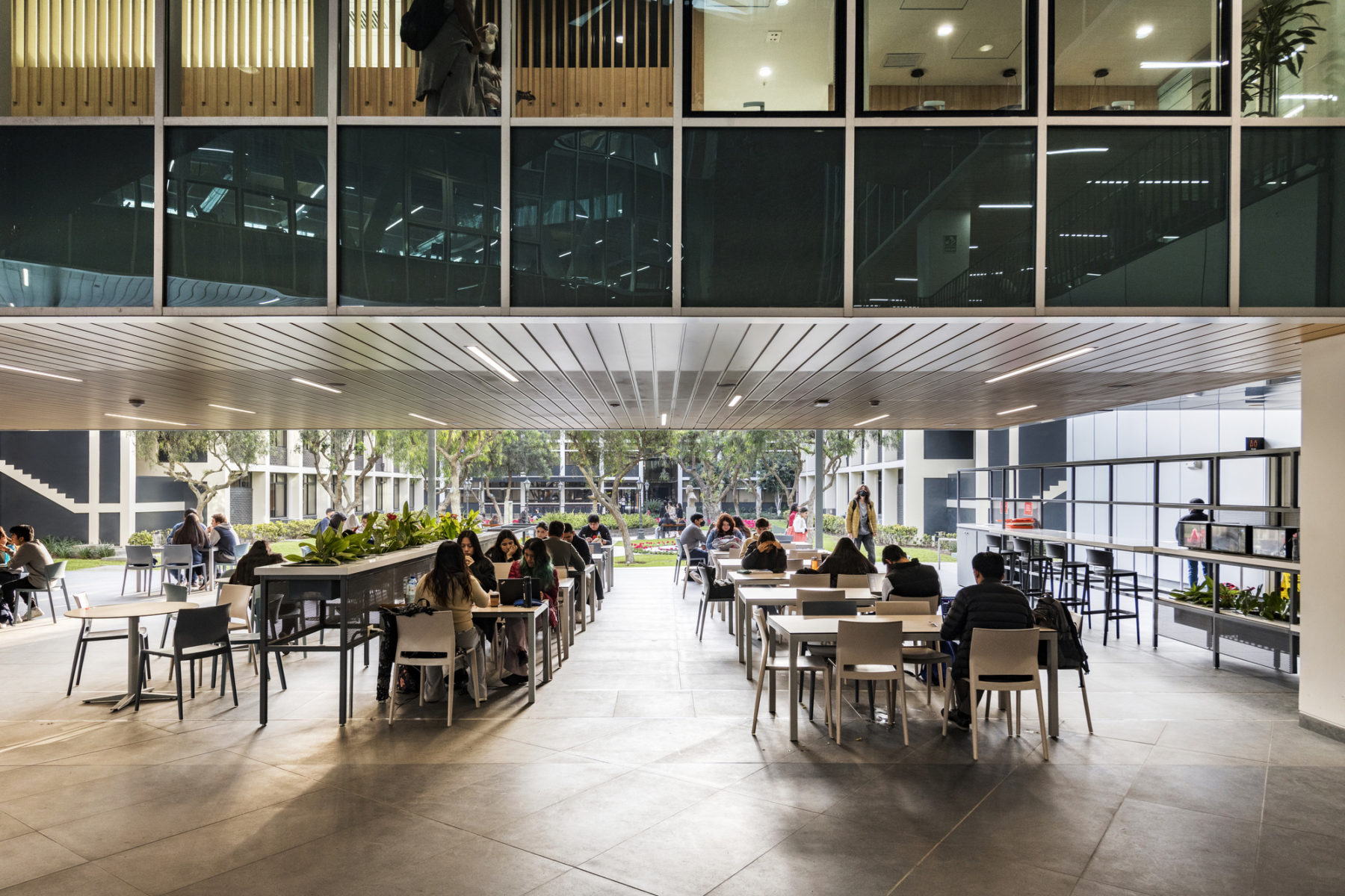 interior photo of study terrace with students studying at tables and chairs tucked beneath program space above