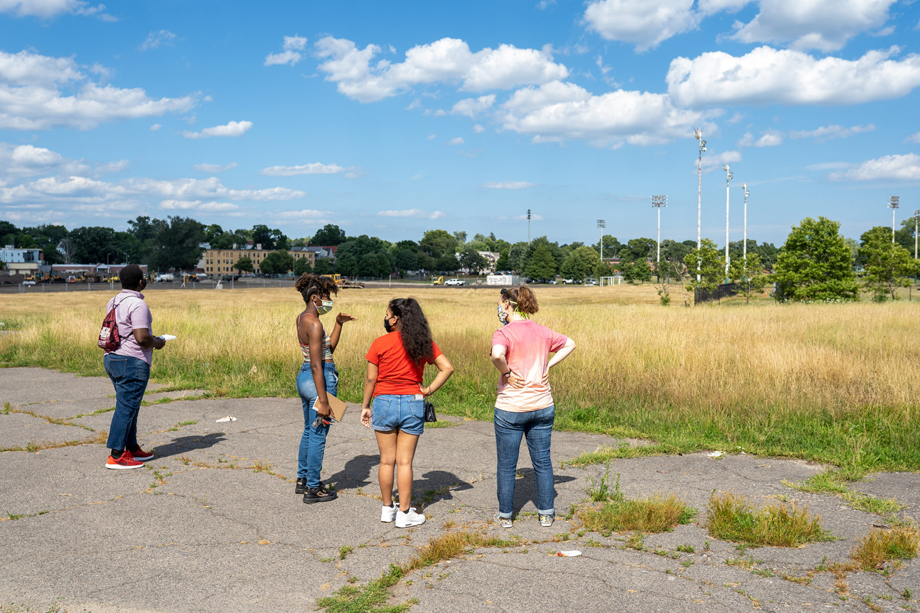 four people looking out onto a field and talking