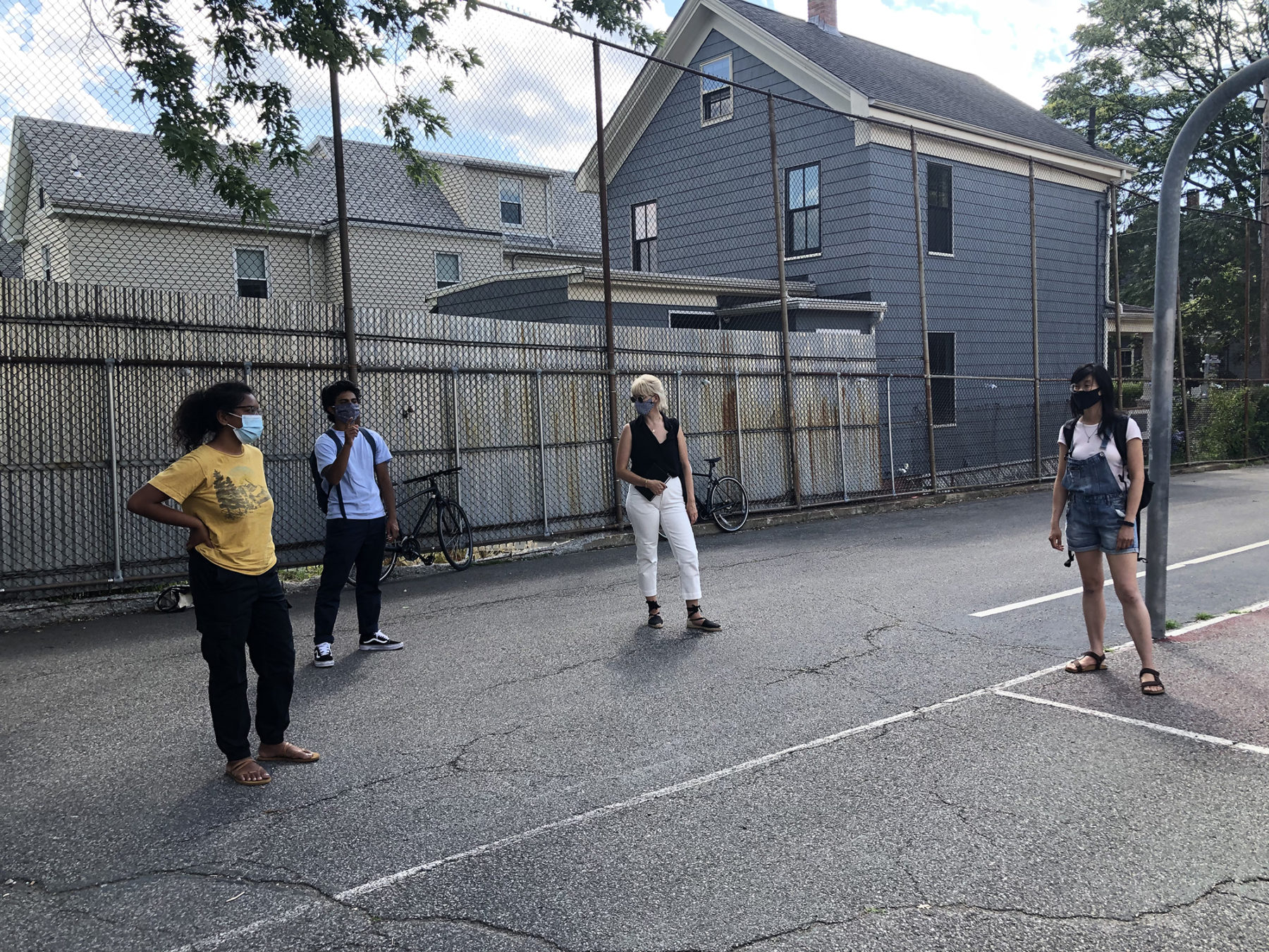 four people standing and talking in a parking lot