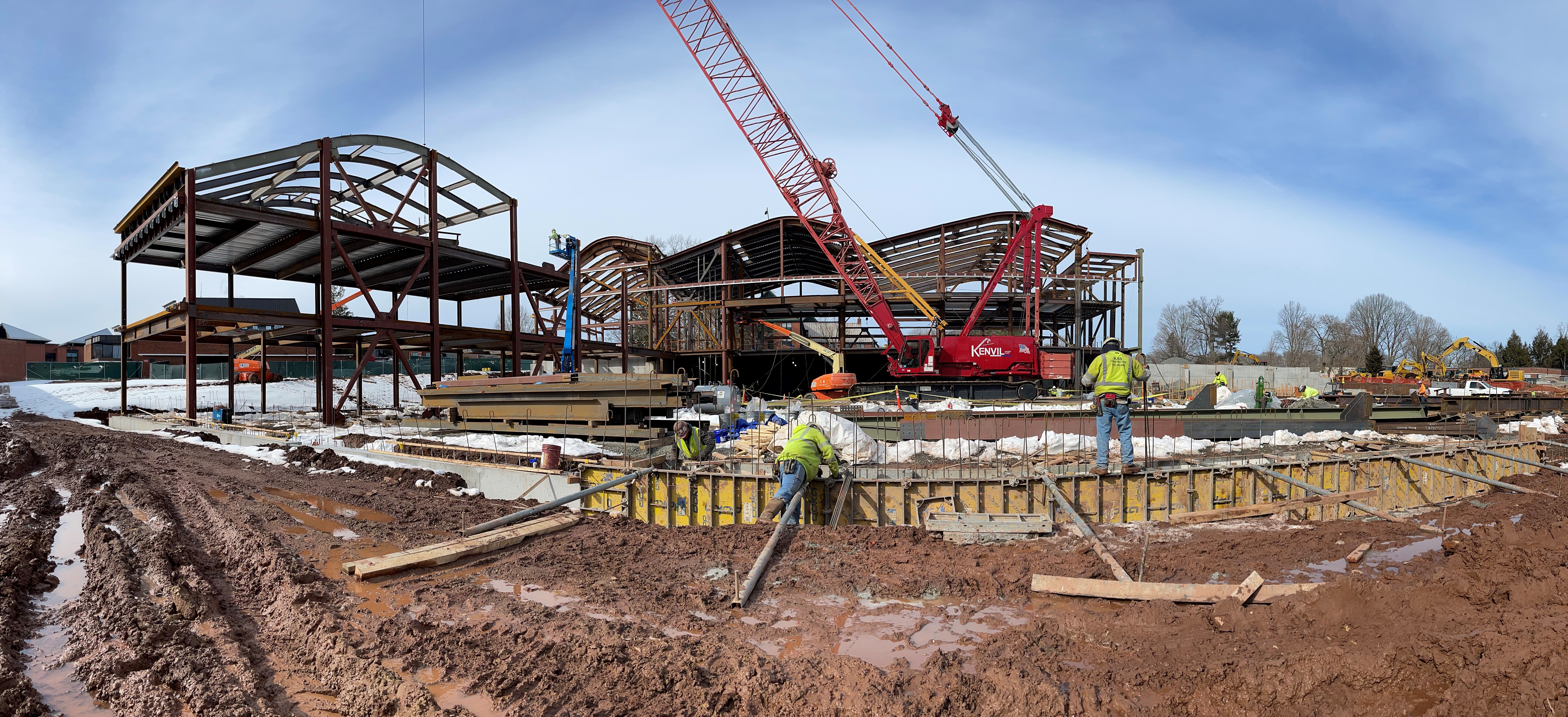 Photograph of entire building and construction site with crane and workers