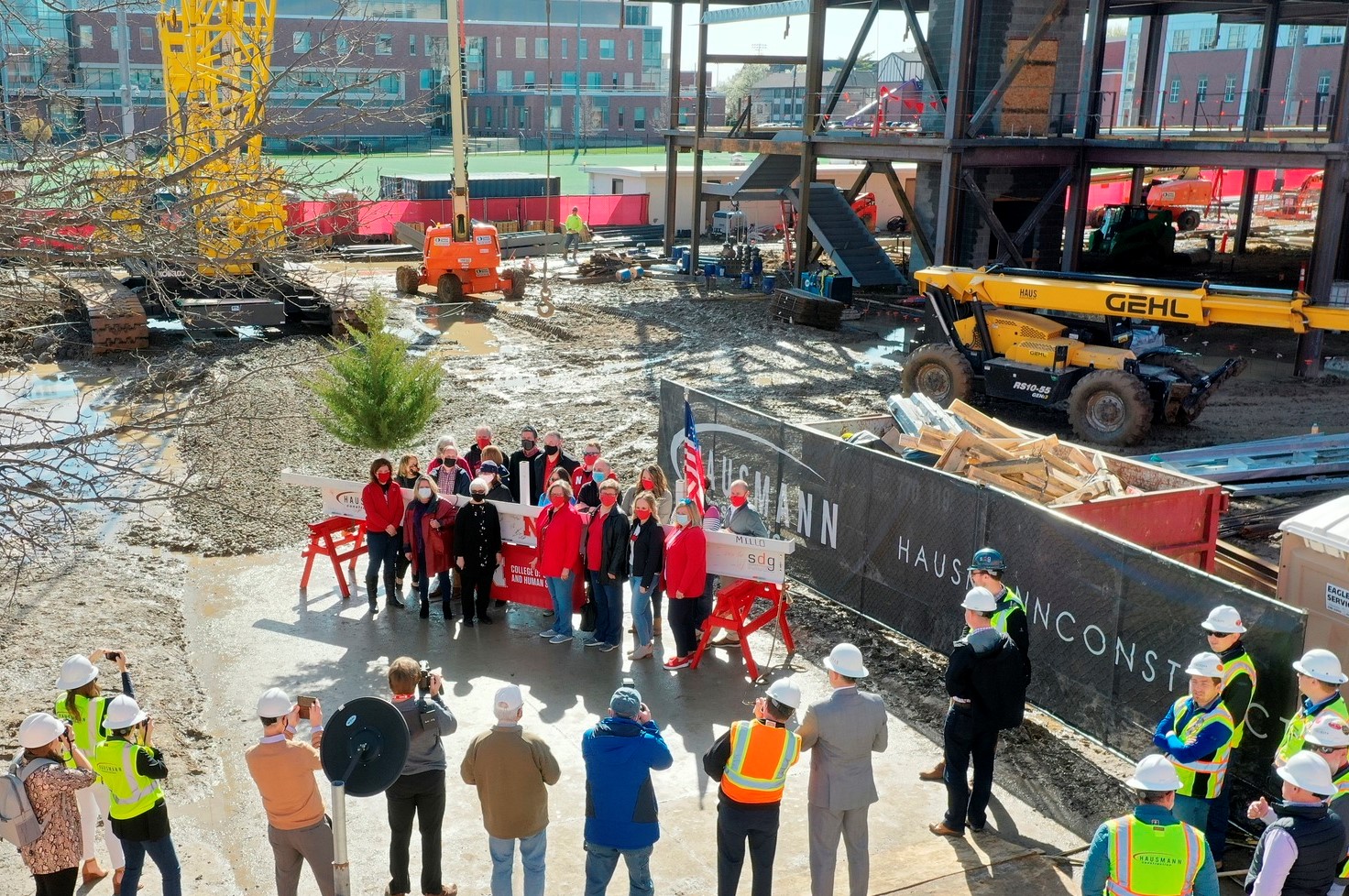 People gather in front of the beam used in the topping off ceremony