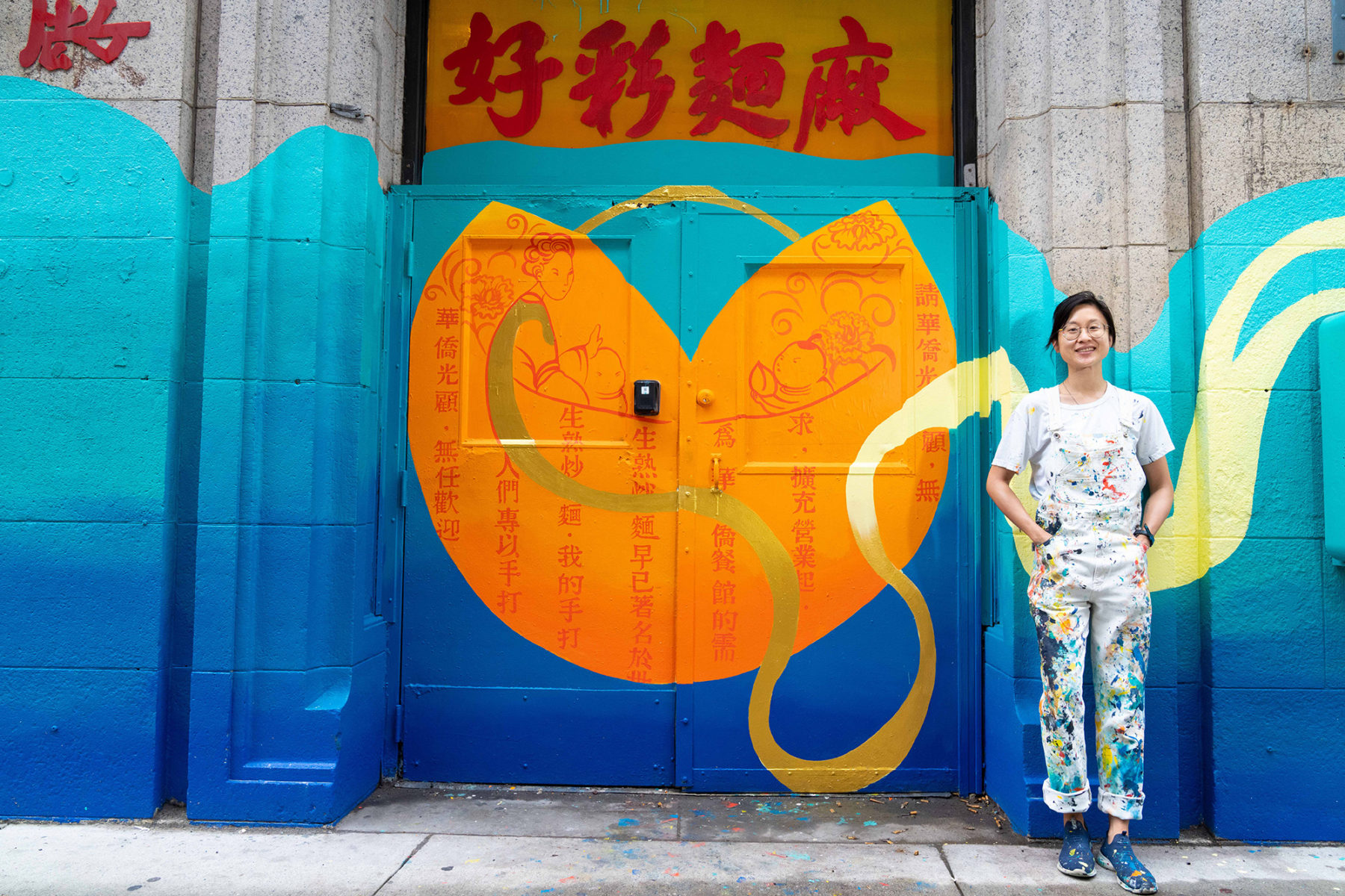 Artist stands by vibrant colored mural painted over doors