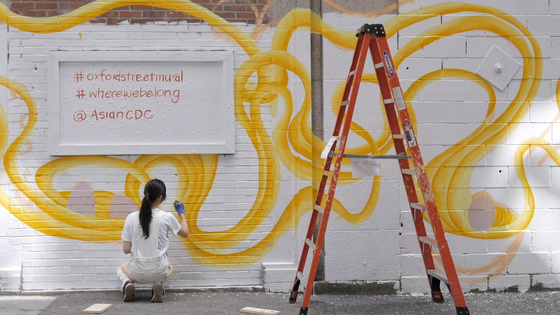 Artist crouches to paint detail on mural