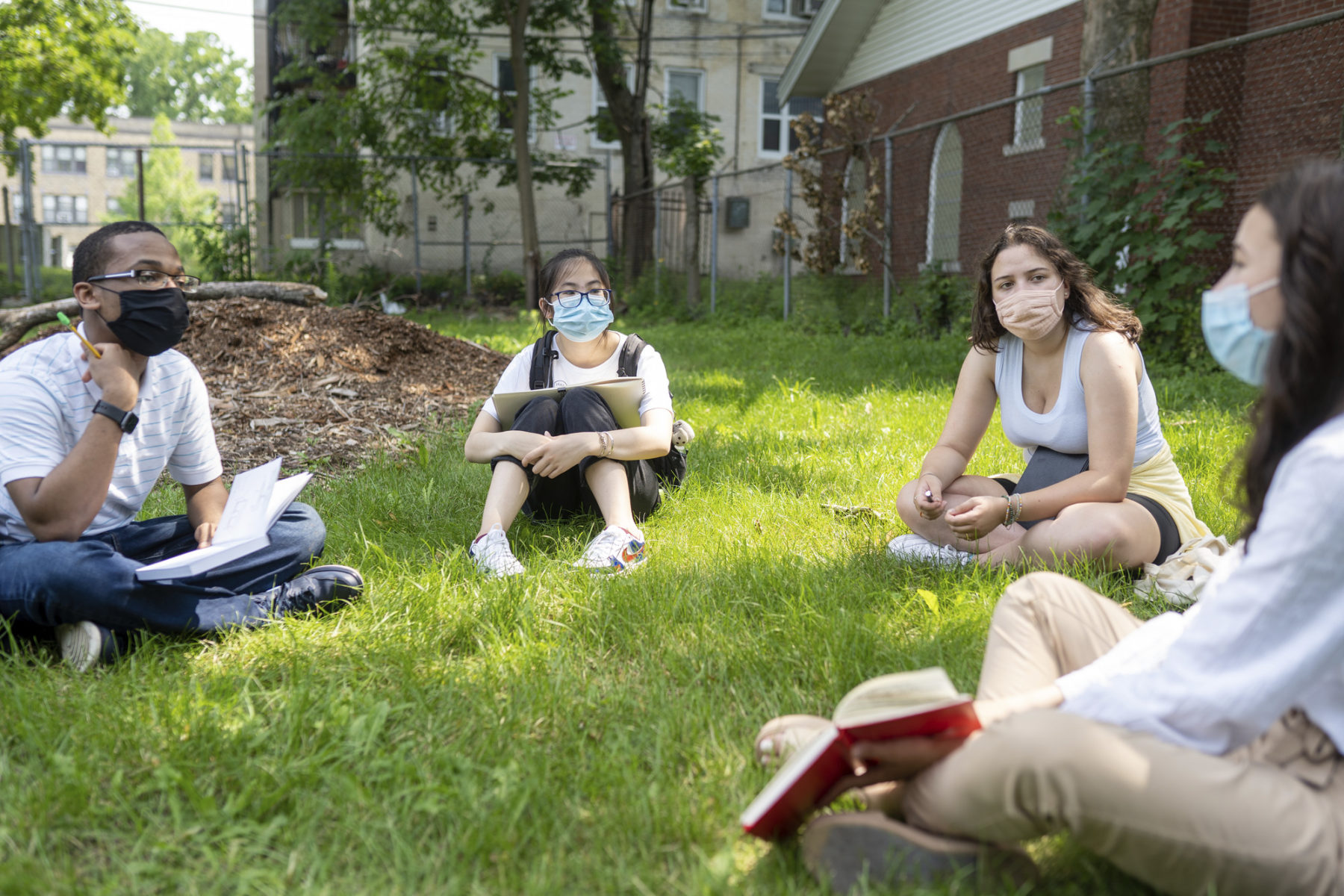 Students sitting in the grass in a circle wearing face masks