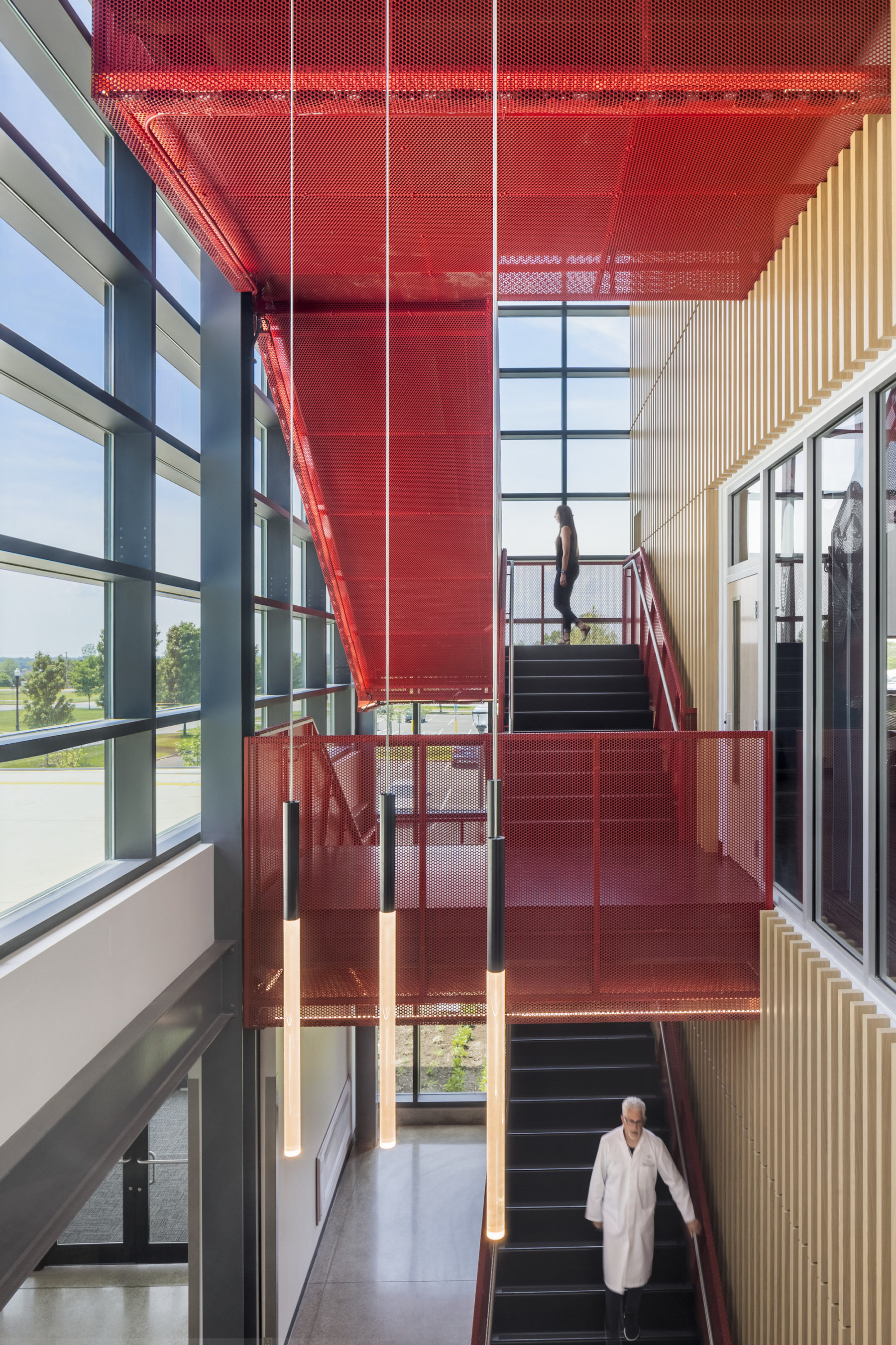 Interior photo of red feature stair. A student climbs up it.
