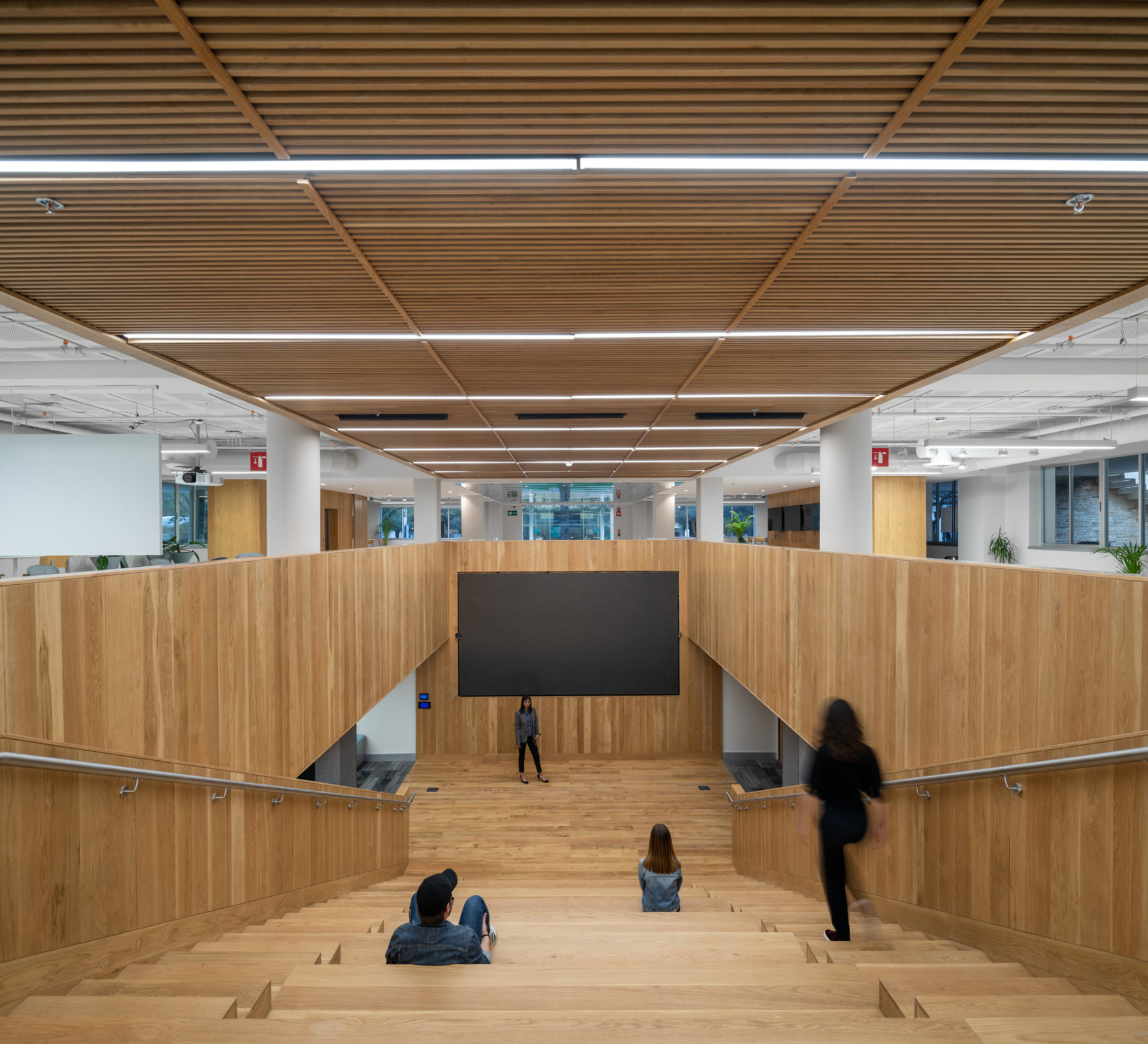 Interior photo looking down amphitheater stairs. A small group of students sit scattered throughout