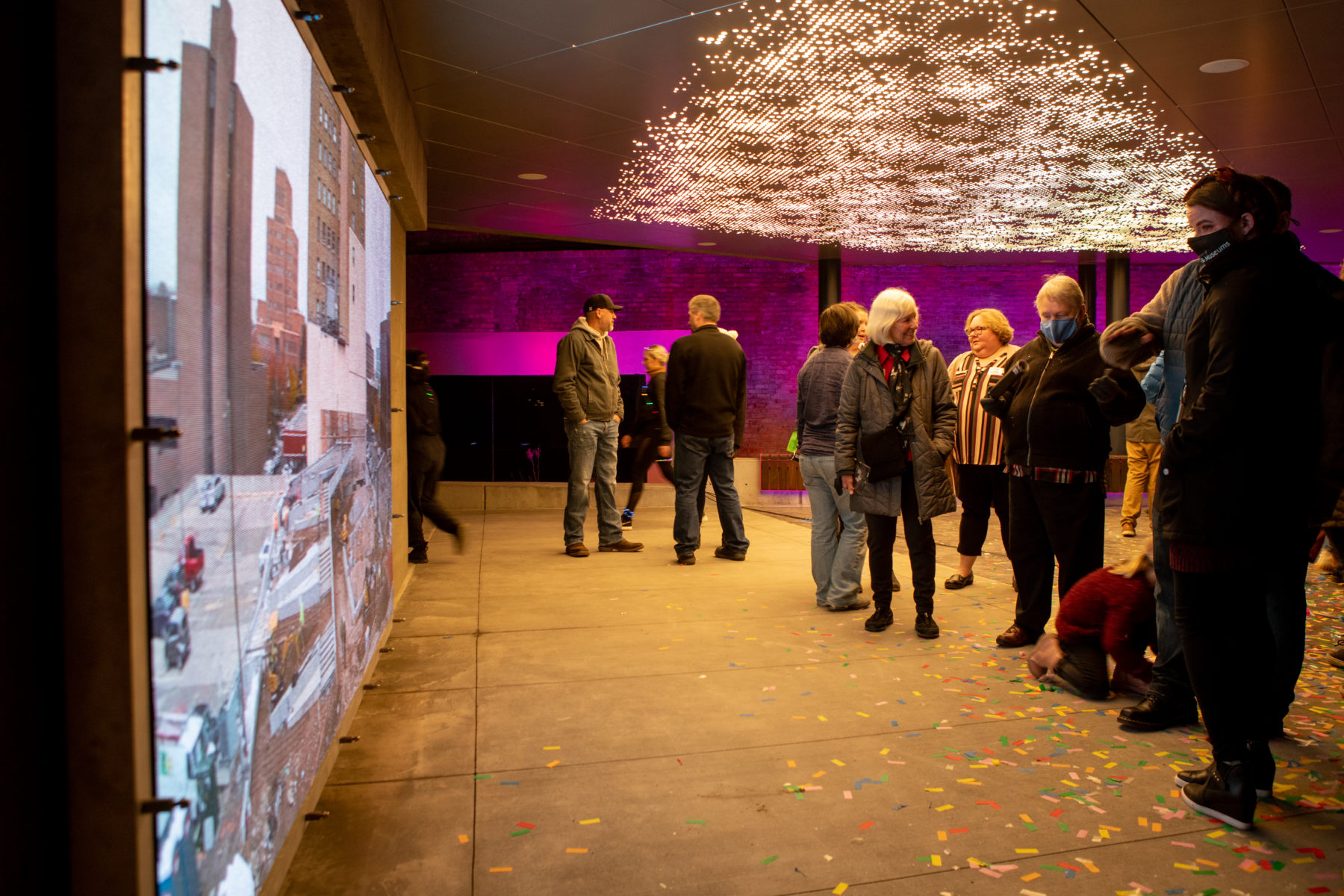 People looking at a timelapse of the construction process and photos of the Dumke Foundation founders that were displayed on the LED screens on the plaza’s walls.