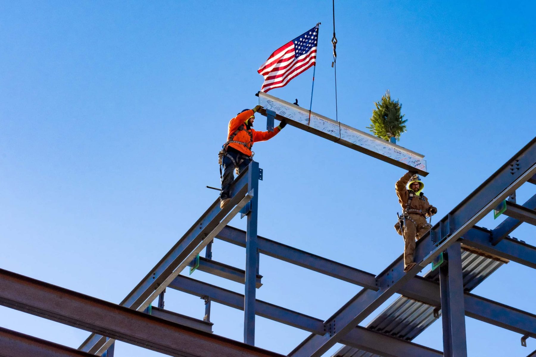 Construction workers erect the final steel beam on the structure