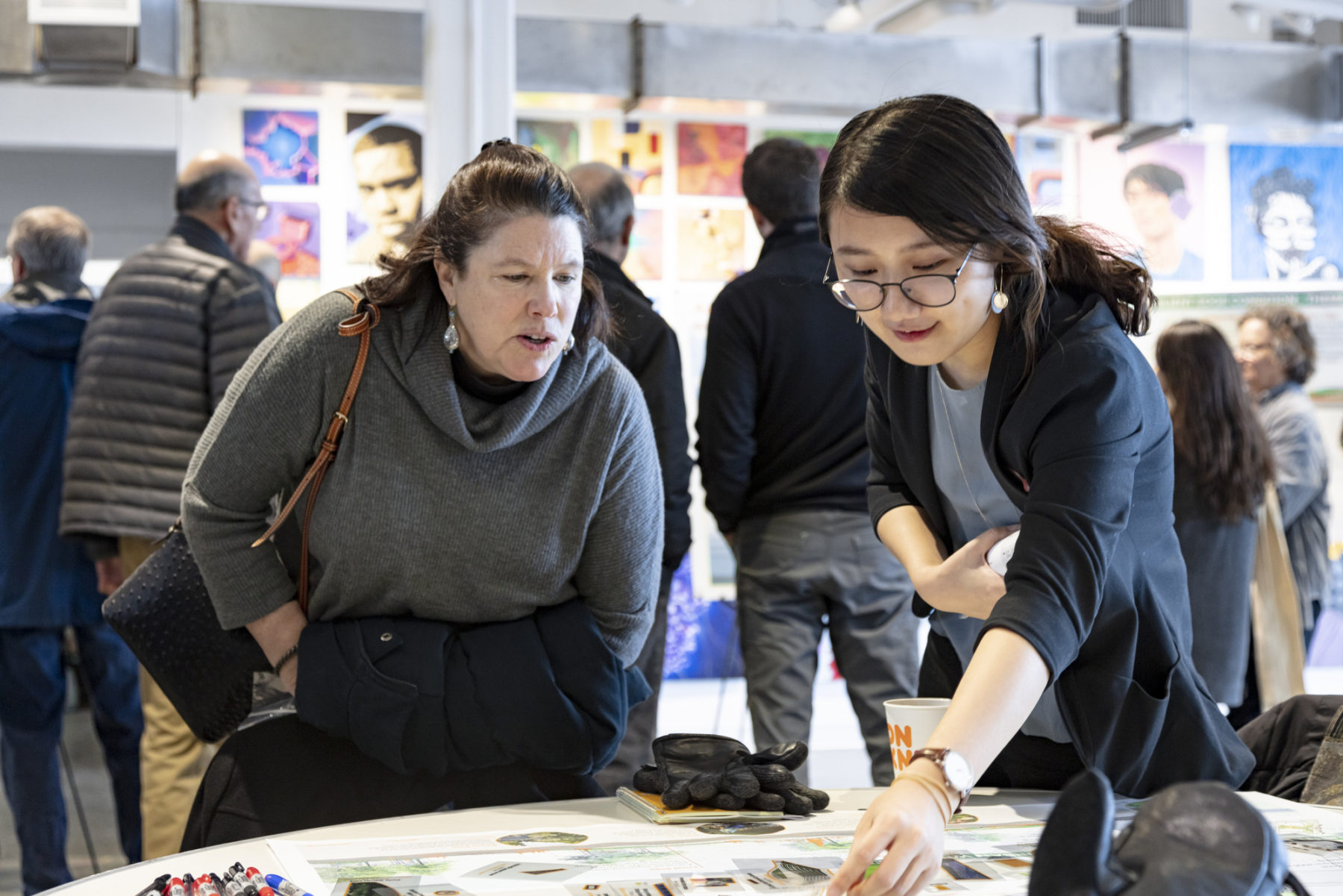 photo of two women at public engagement session. one points to a plan on the table in front of them