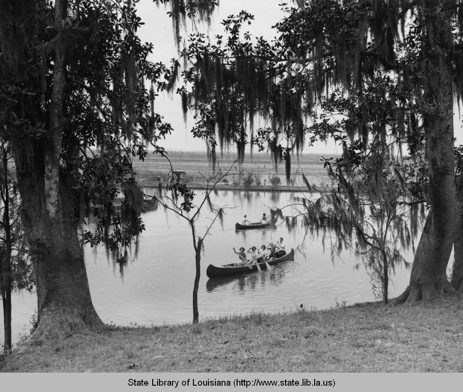 historic photo of site with trees along the lakefront in the foreground and two canoes in the center