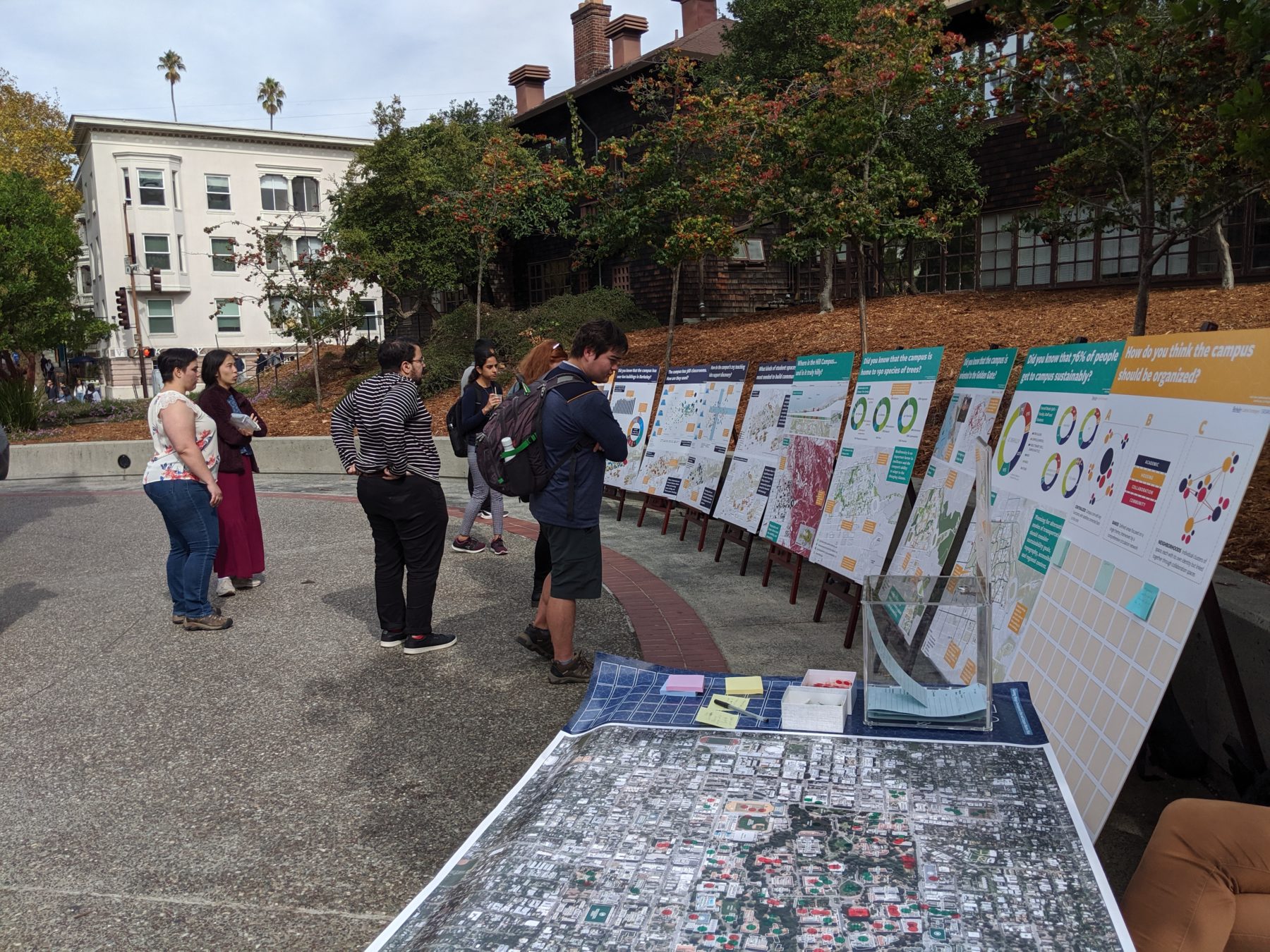 People looking at information graphic boards on a main campus thoroughfare